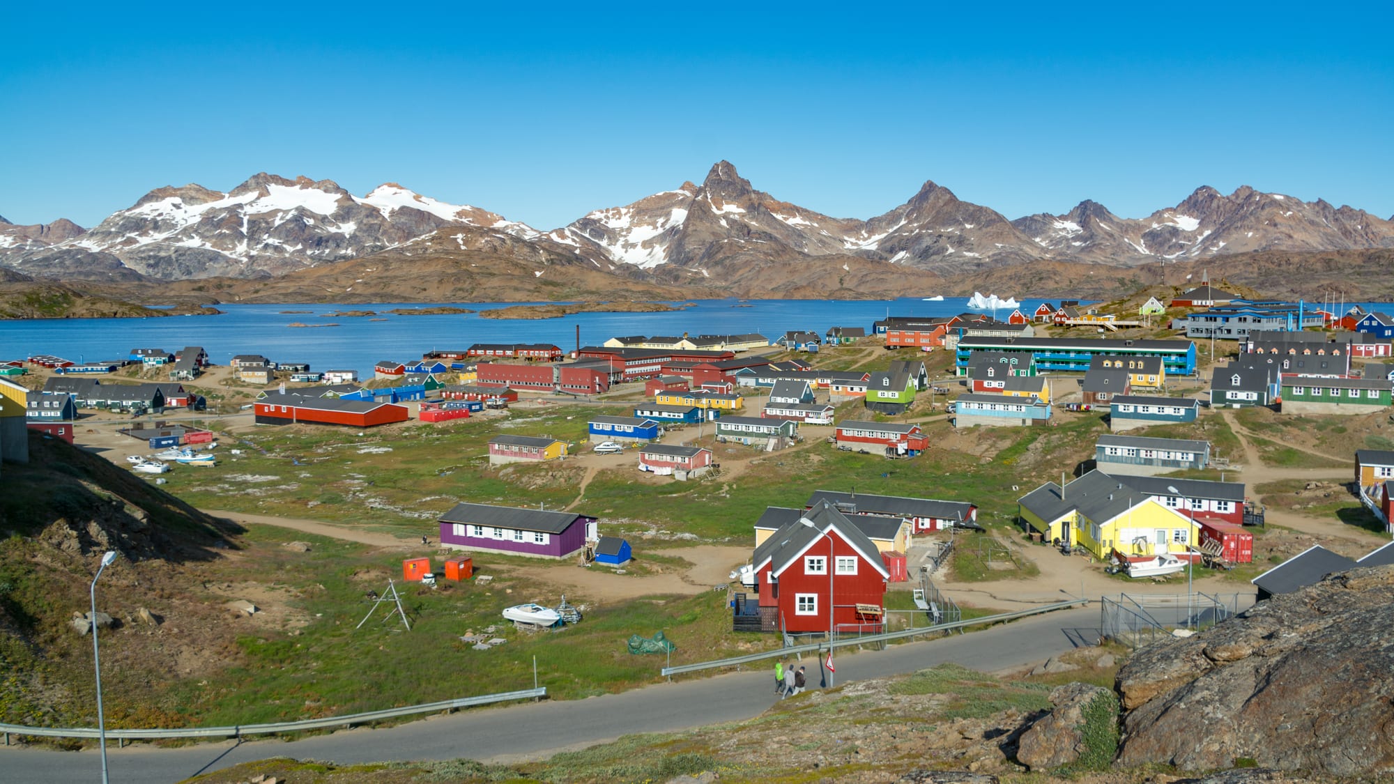 Colourful houses on a snowy hillside above a fjord ringed by sharp peaks