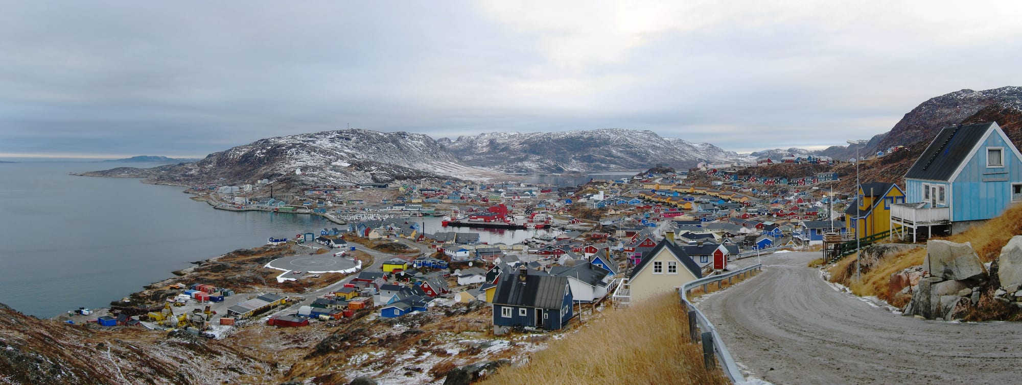Tiers of brightly painted houses rising from a small harbour ringed by snow-dusted hills