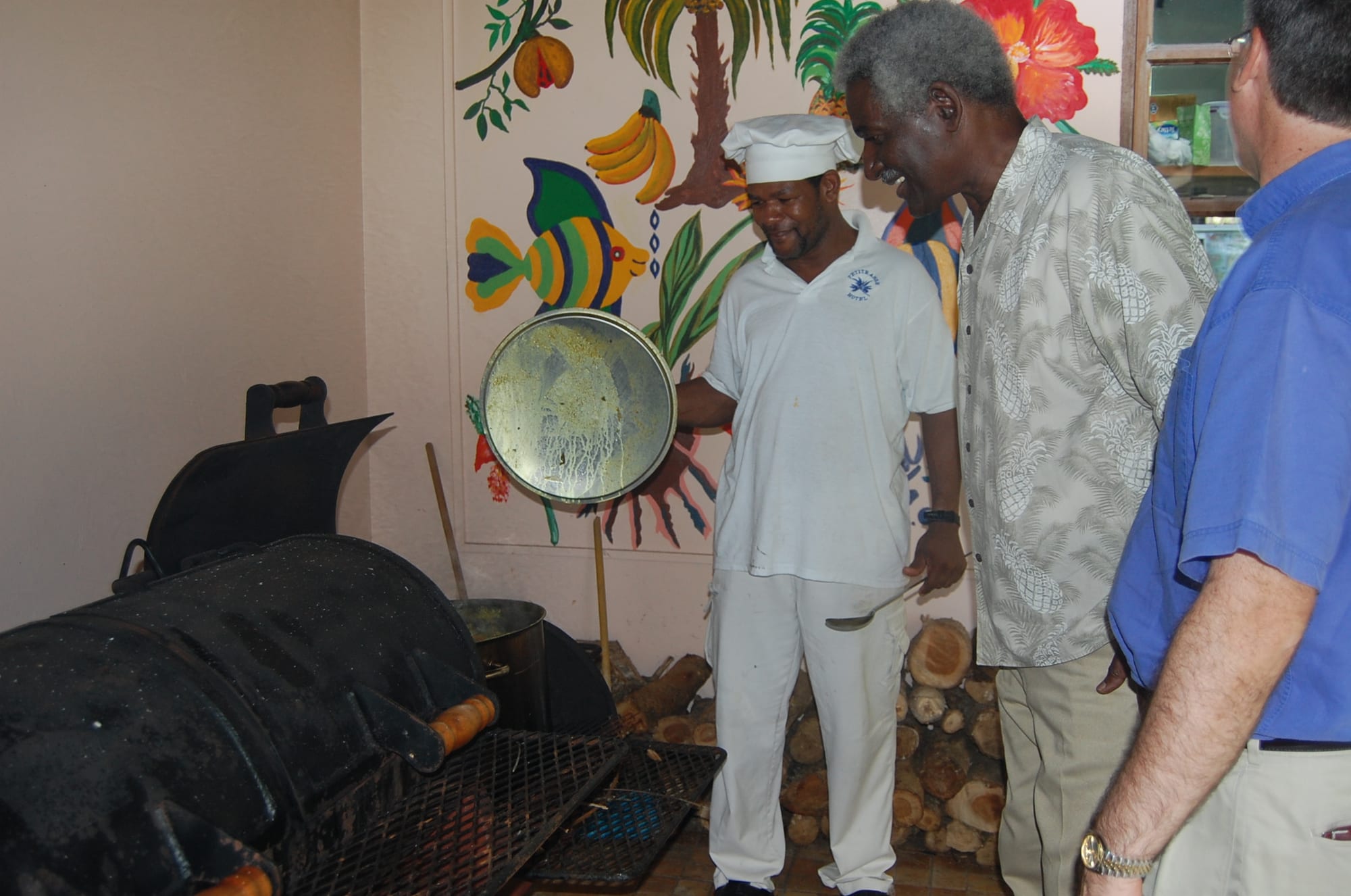 A large pot of stewed vegetables, meat and dumplings being checked over an outdoor fire
