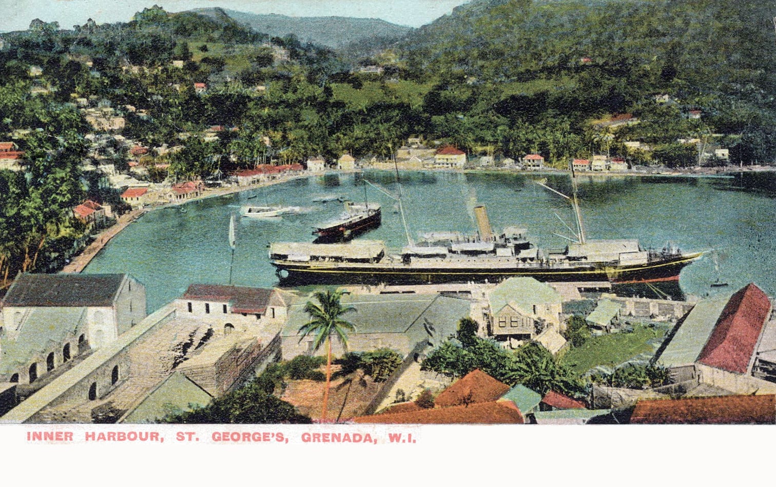 A horseshoe harbour lined with red-roofed colonial buildings climbing green hills