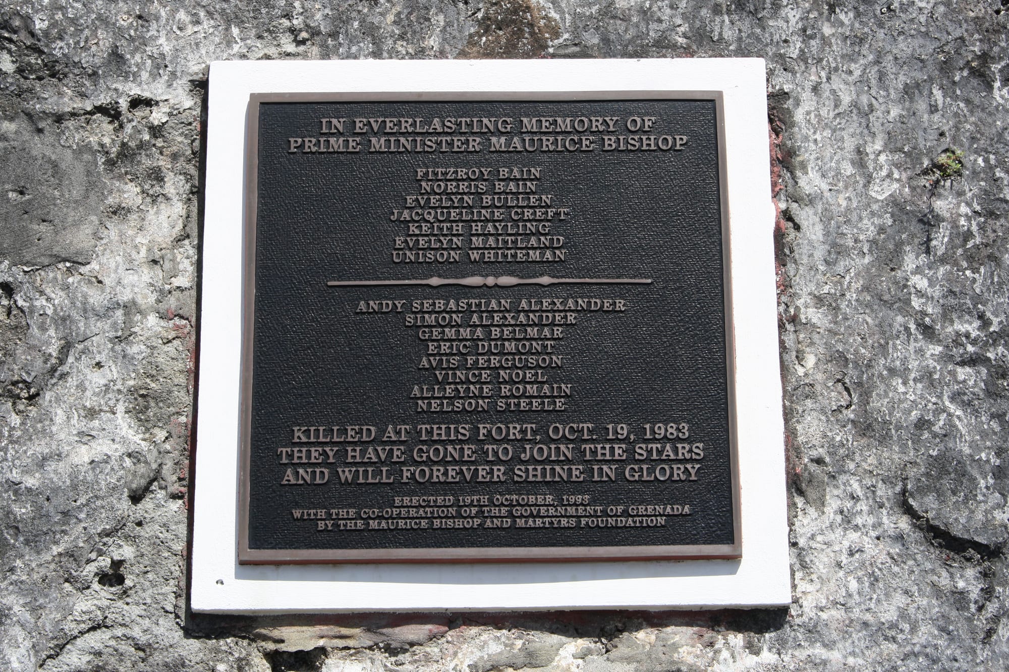 A memorial plaque to Maurice Bishop and others mounted on a stone wall at Fort George