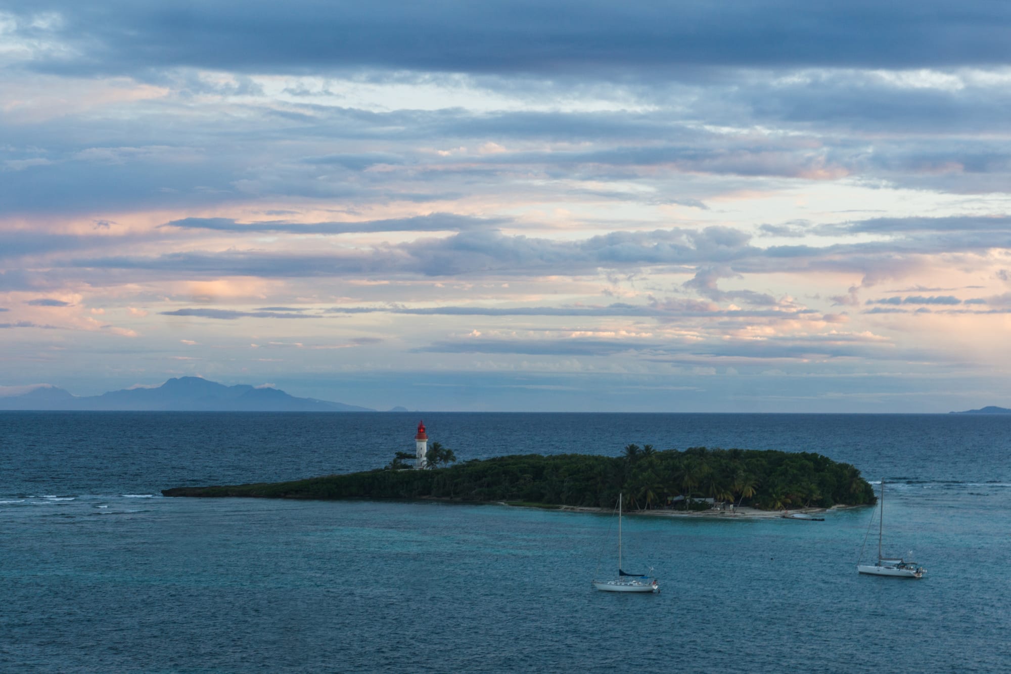 A small islet with a lighthouse and a strip of beach, close to a built-up shore