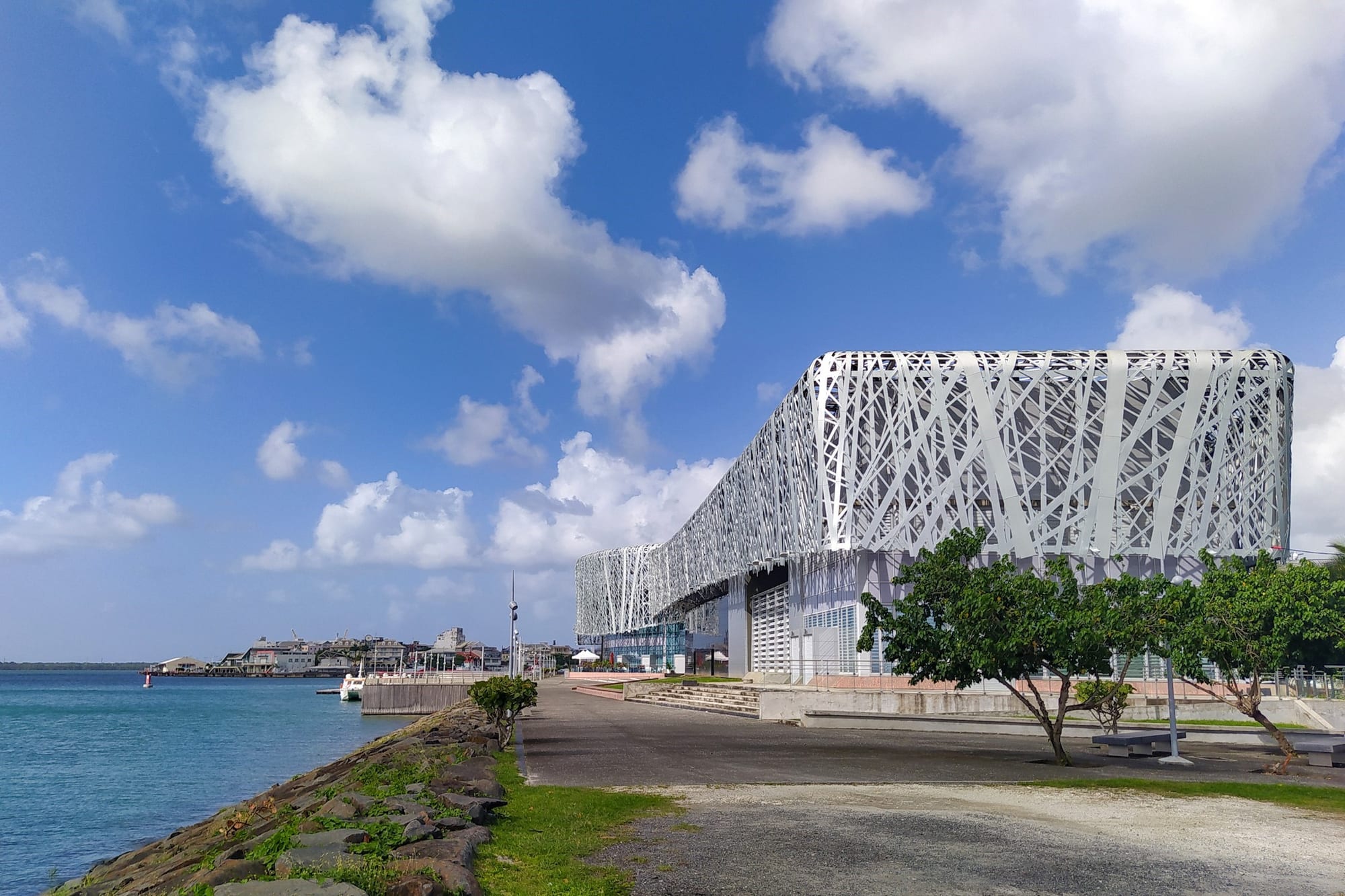 A long modern building clad in silver latticework beside the sea