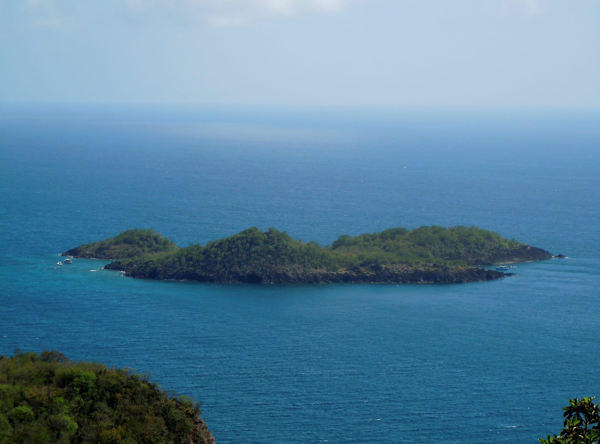 Two small forested islands just offshore in calm blue water