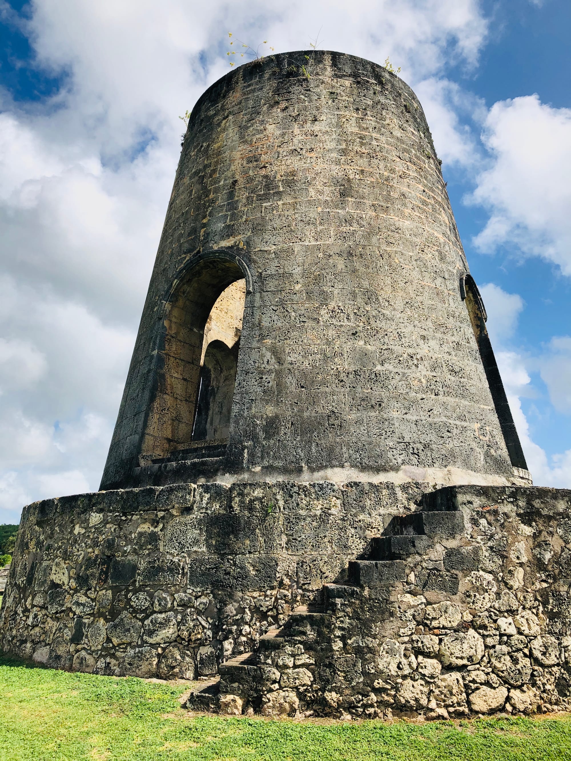 A restored stone sugar-mill tower standing in a field of cane