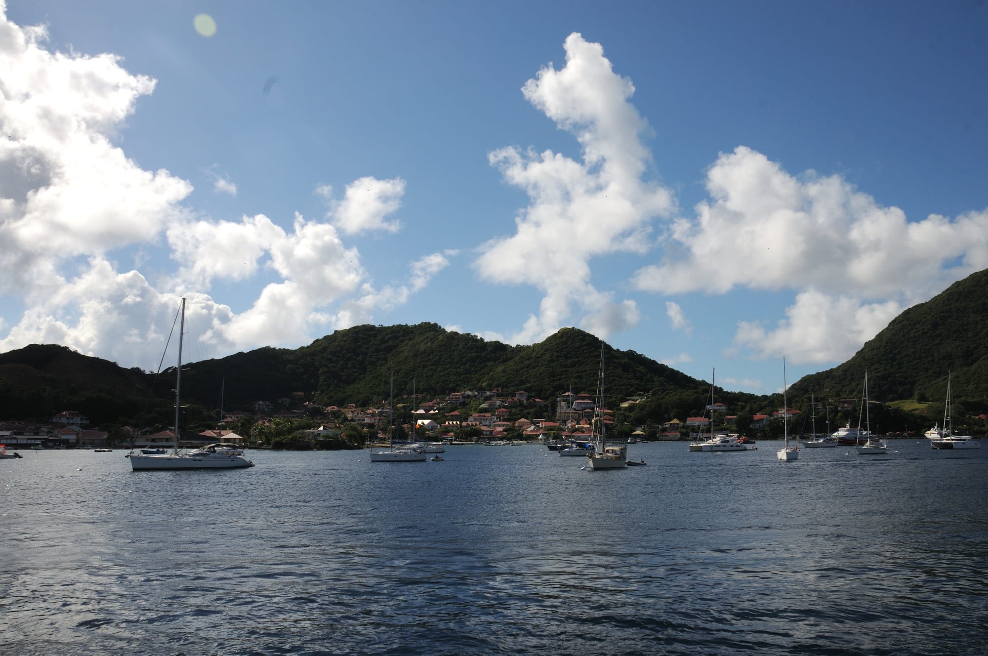 Red-roofed houses around a bay of clear water with green islands beyond