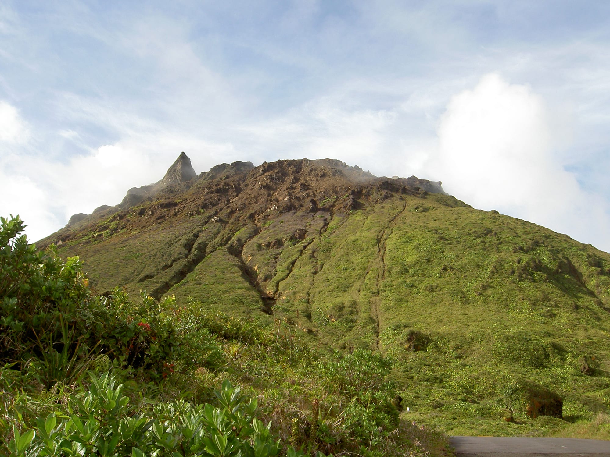 Steam venting from bare rock at the cloud-wrapped summit of a tropical volcano