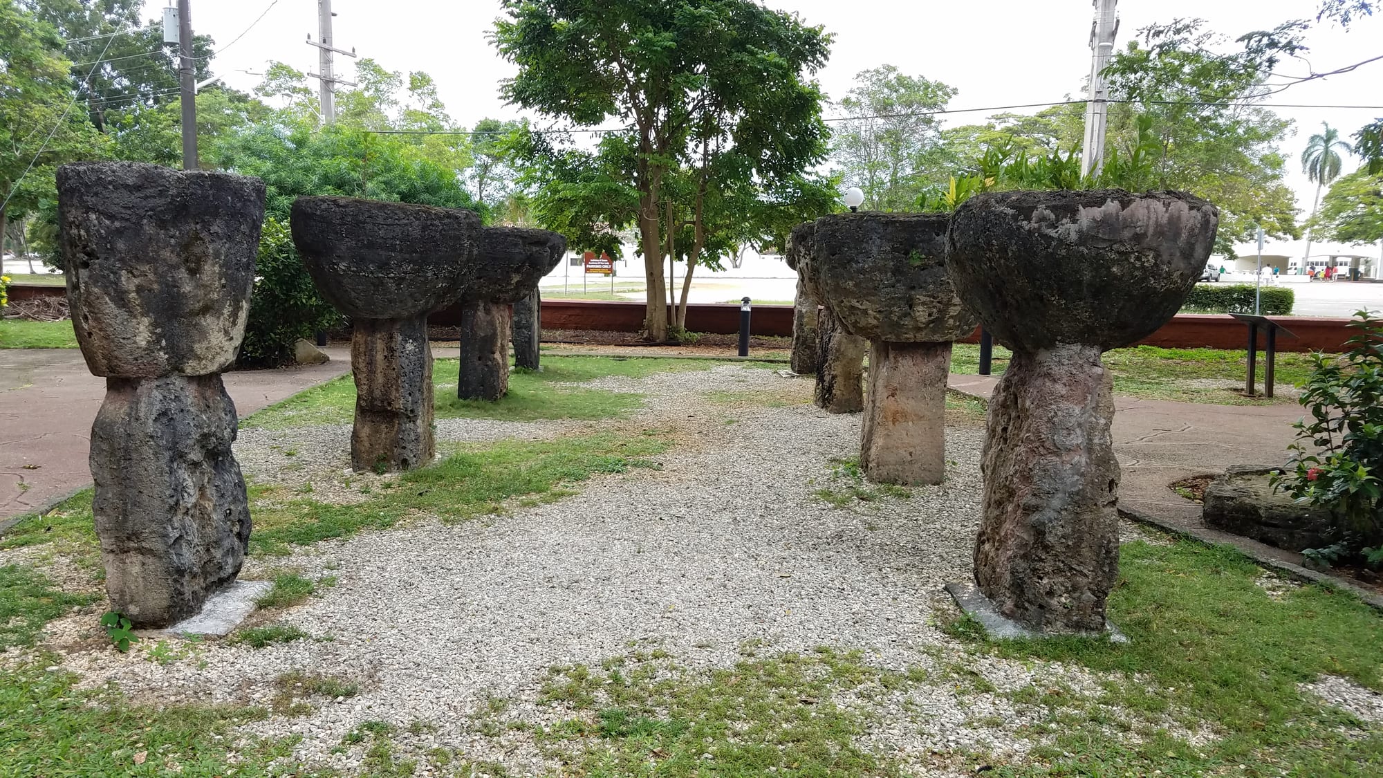 Rows of two-part stone pillars — a column topped by a hemispherical cap — on a lawn