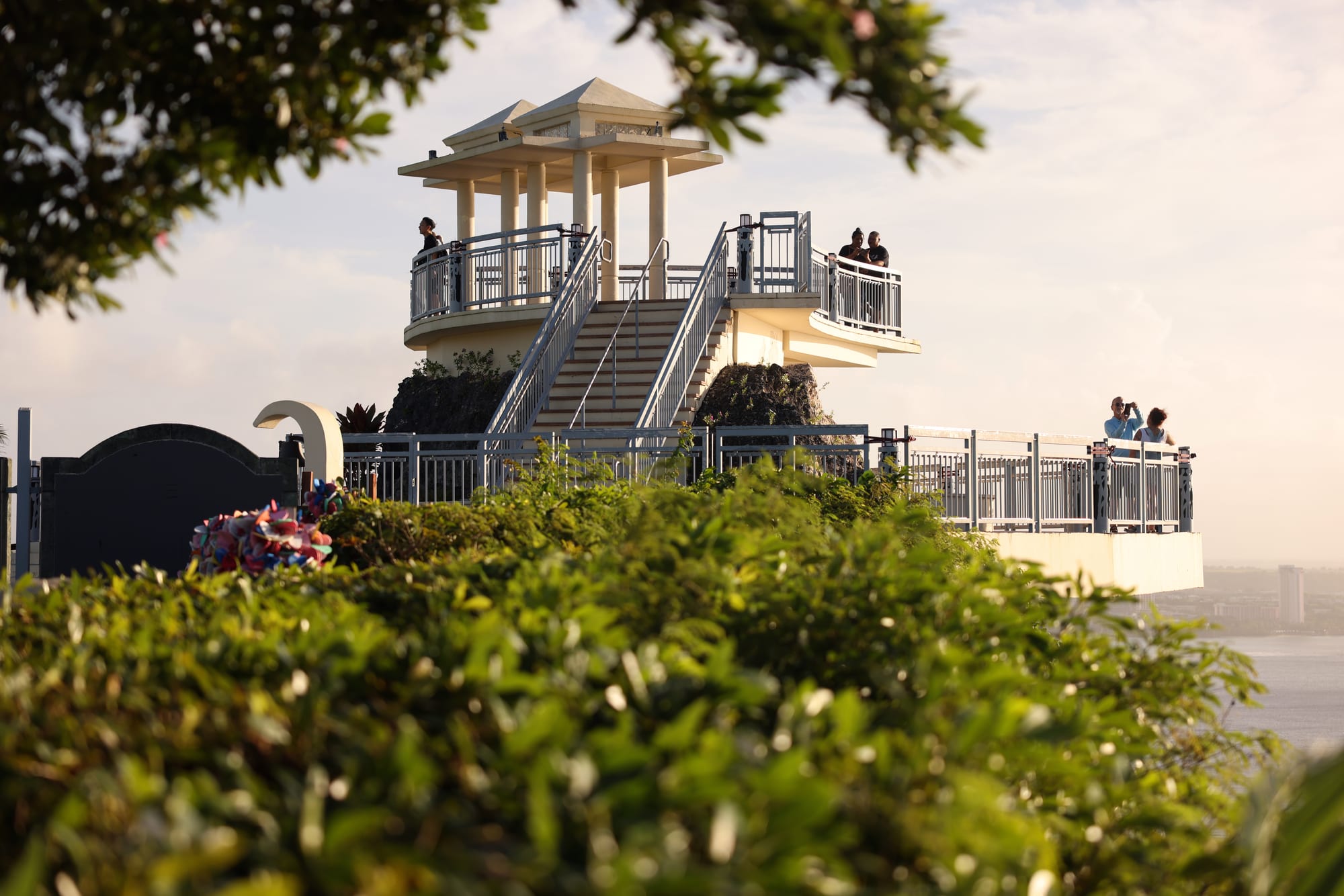 A high cliff platform with railings above the sea, with visitors looking out