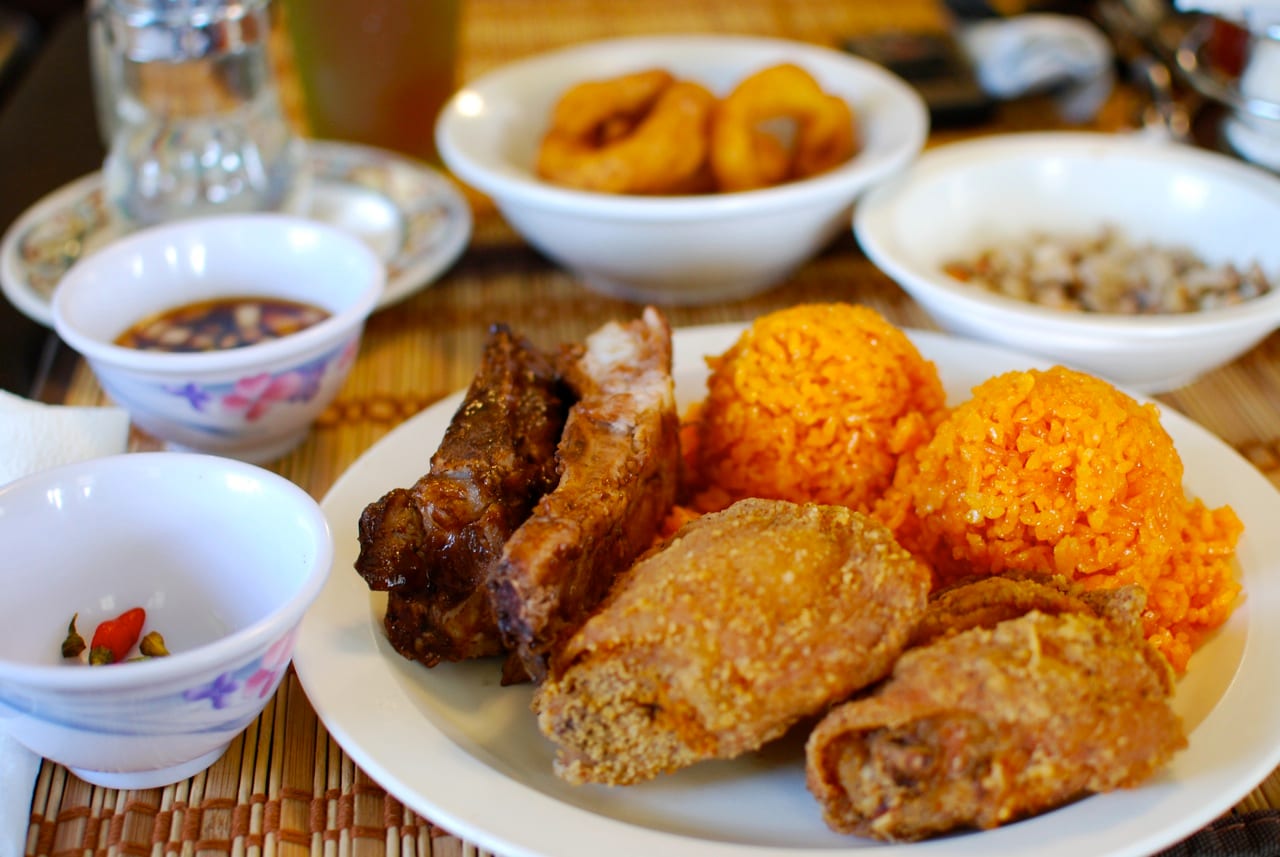 A plate of grilled meat, rice and side dishes