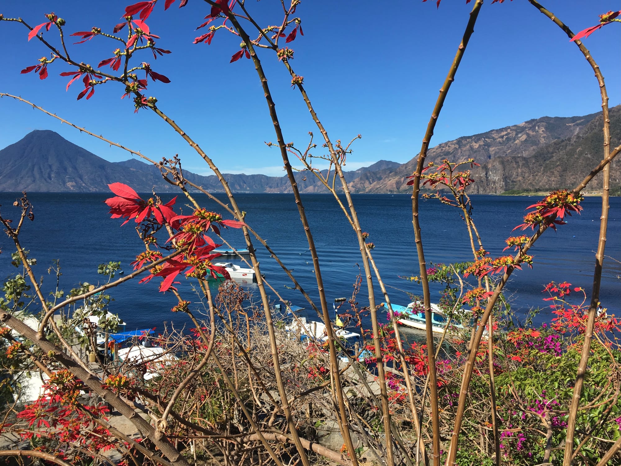 A deep blue lake ringed by steep hills and three volcanic cones