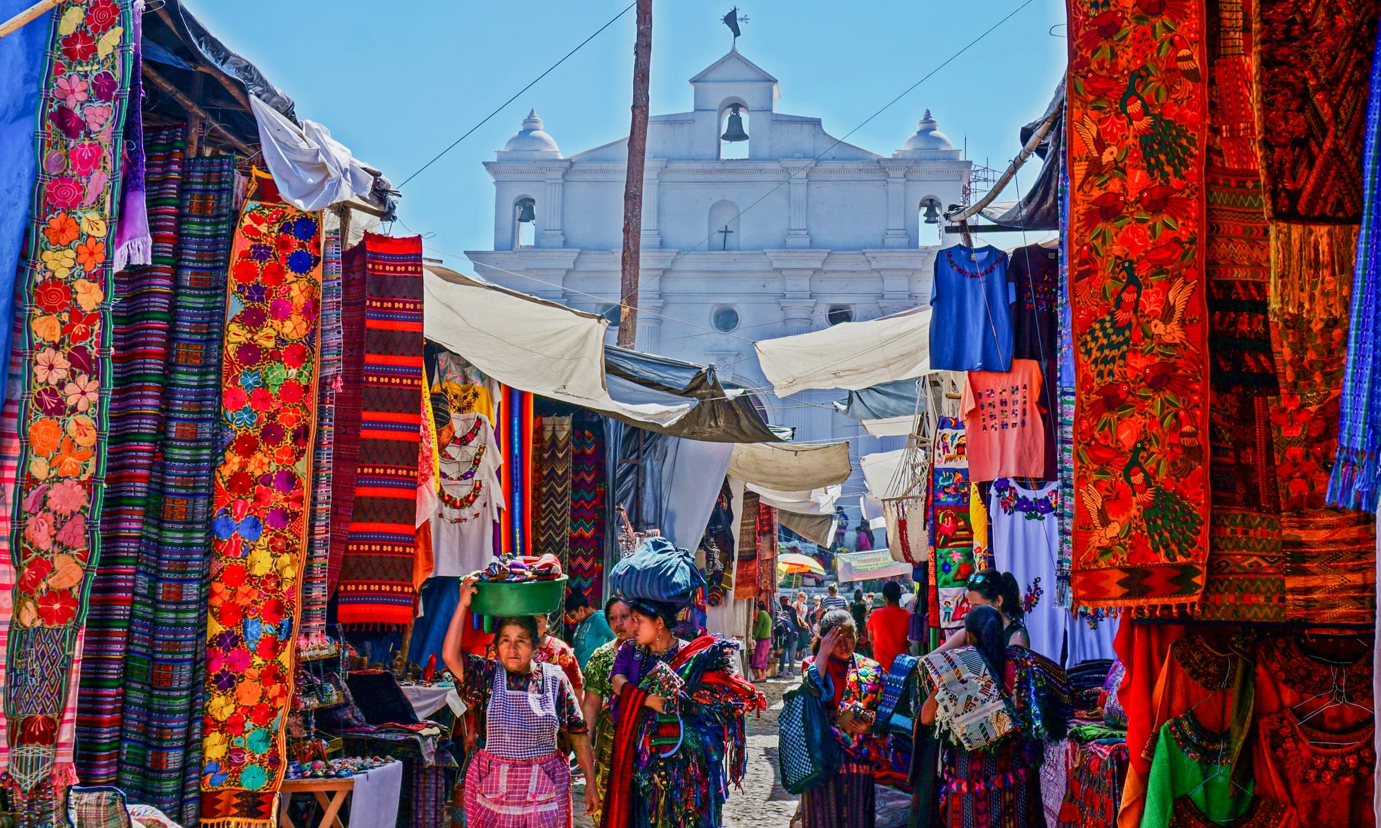 A crowded outdoor market with colourful stalls and awnings