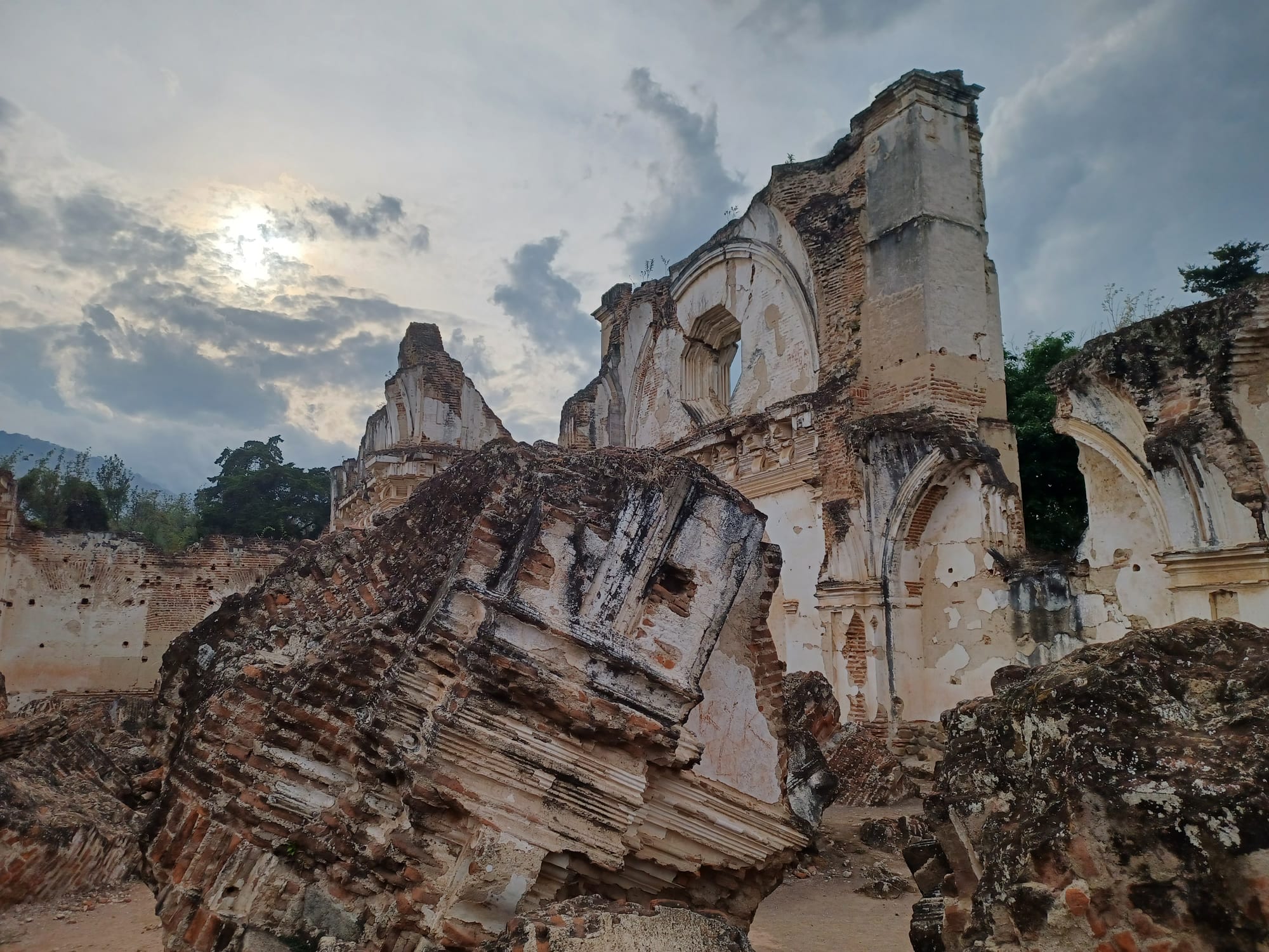 Huge fallen blocks of brick and plaster masonry lying in front of the roofless, cracked walls of a ruined colonial church
