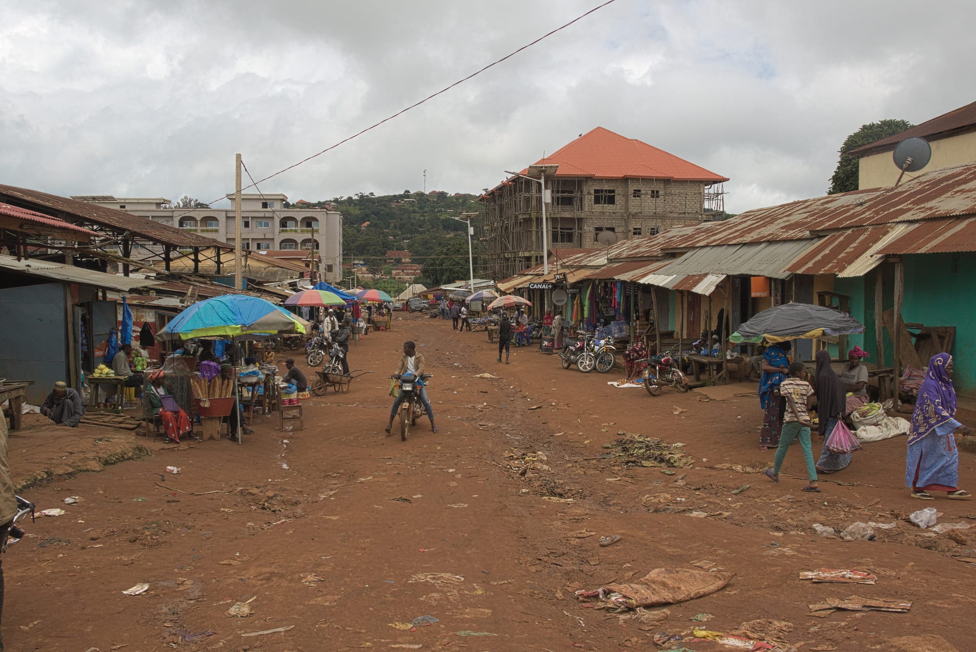 A quiet small-town street with low buildings and hills behind