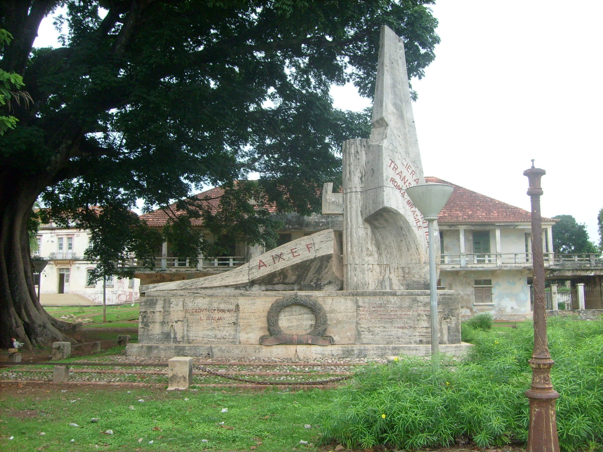An overgrown colonial monument and square with faded grand buildings behind