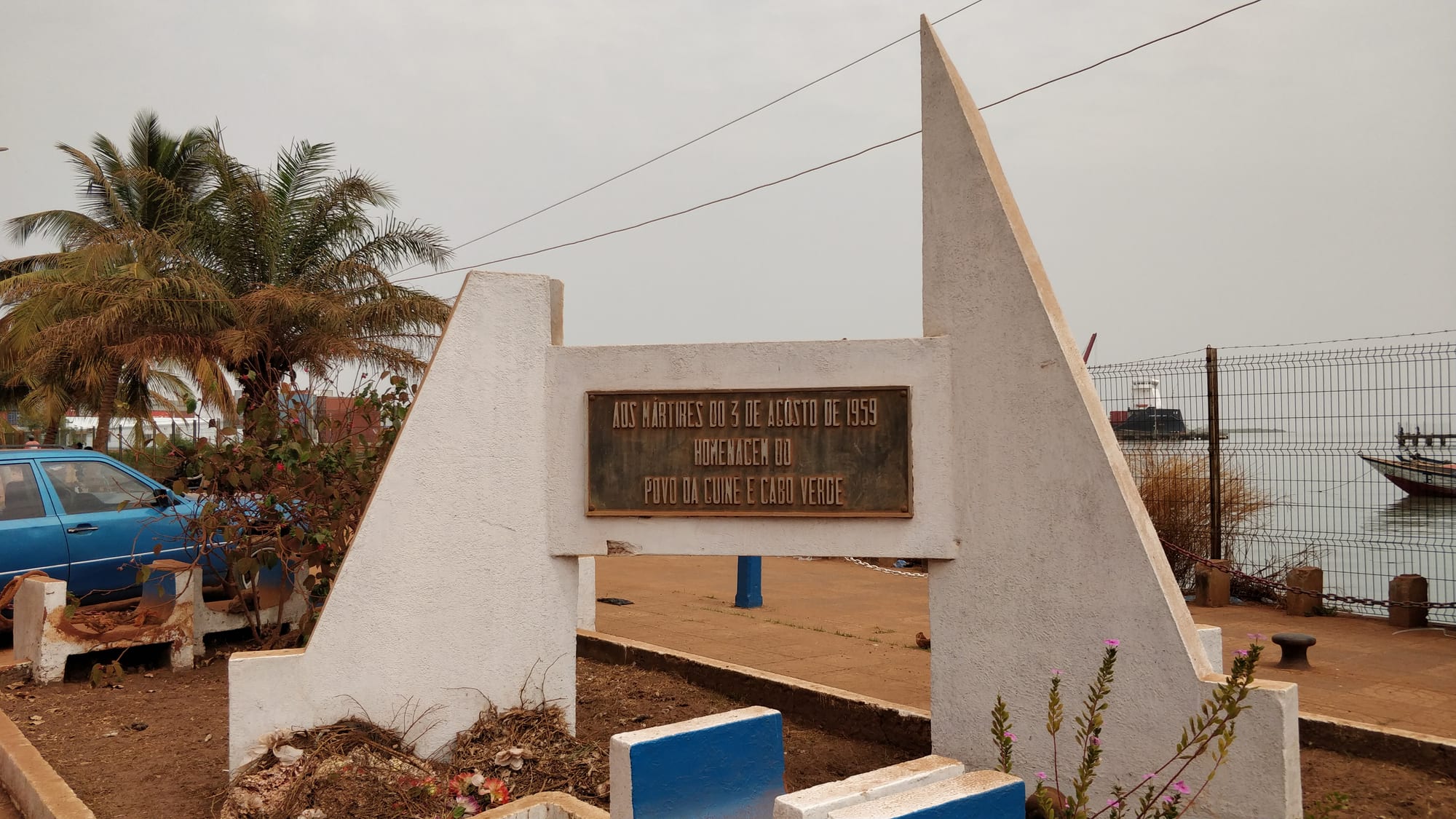A tall black sculpture of a clenched fist rising from a base, by the Bissau waterfront