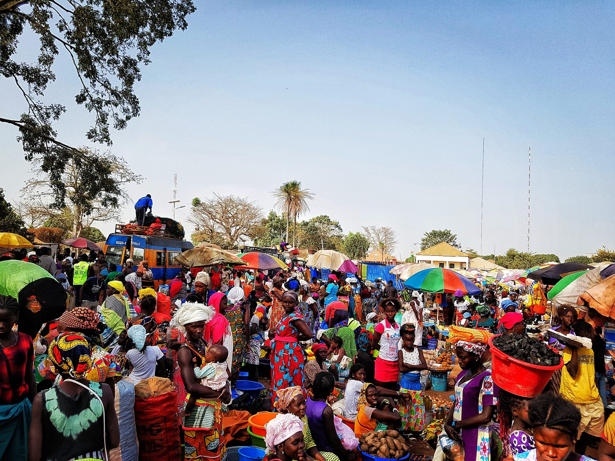 An outdoor local market with vendors and produce stalls