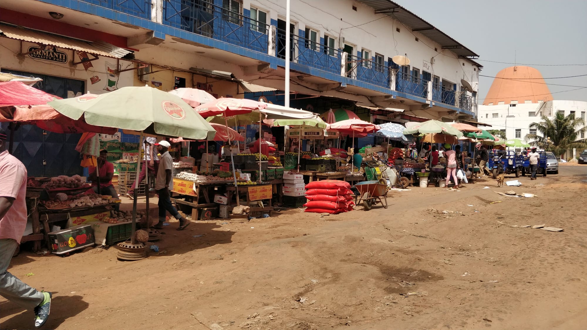 A row of market stalls with colourful umbrellas along a street beside a two-storey building