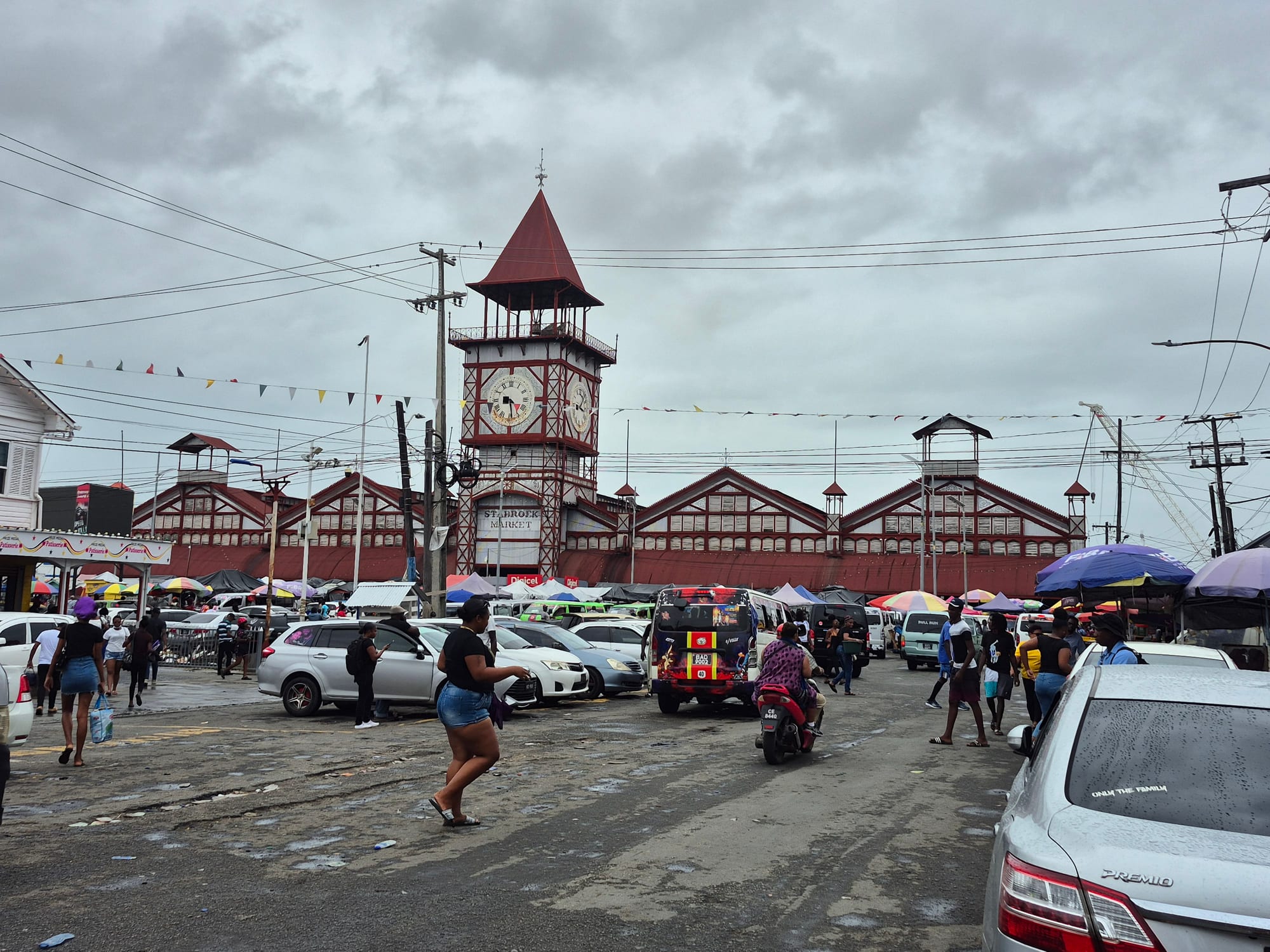 A large iron-framed market building with a prominent clock tower on a waterfront