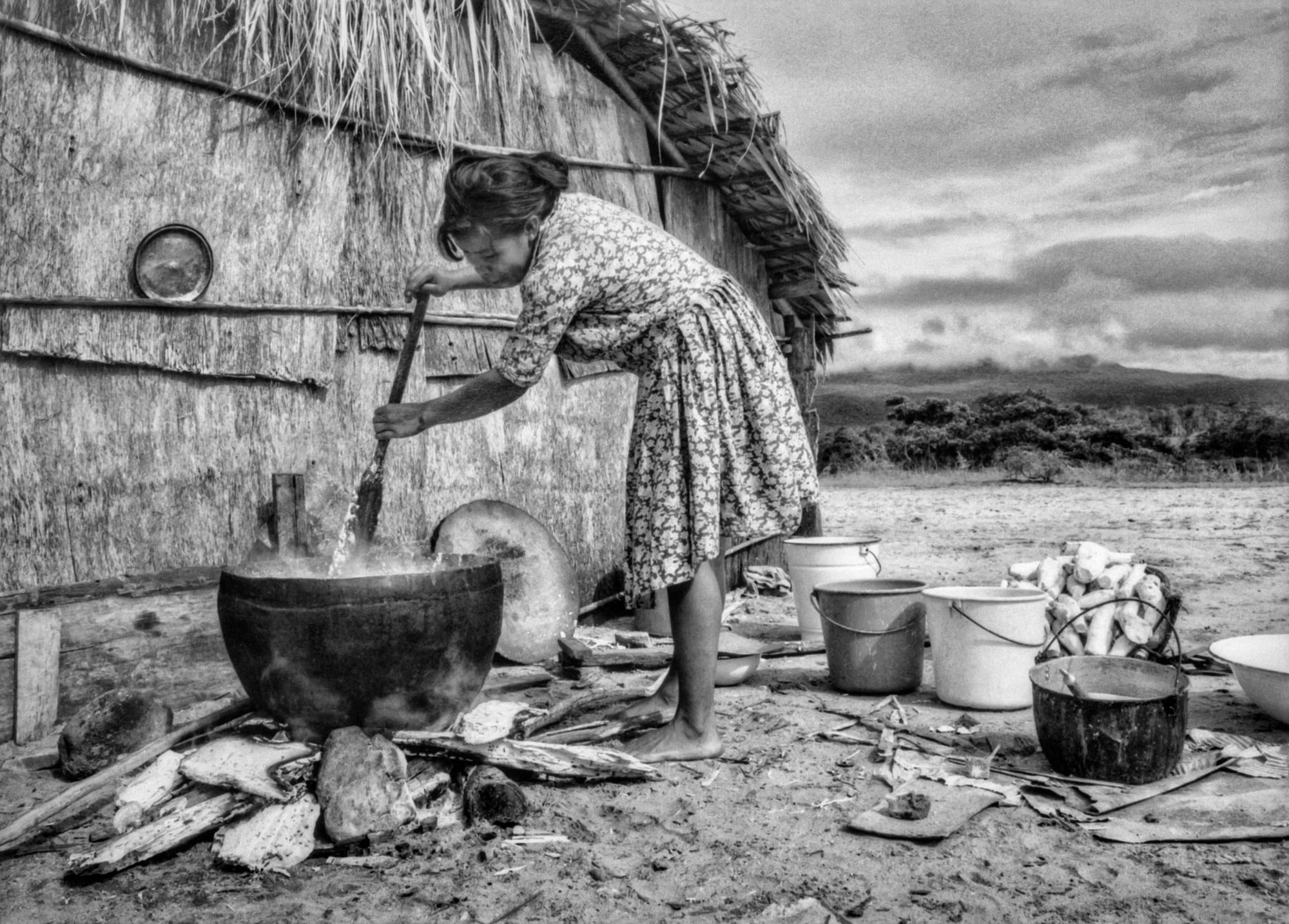 A woman stirring a large pot over an open fire