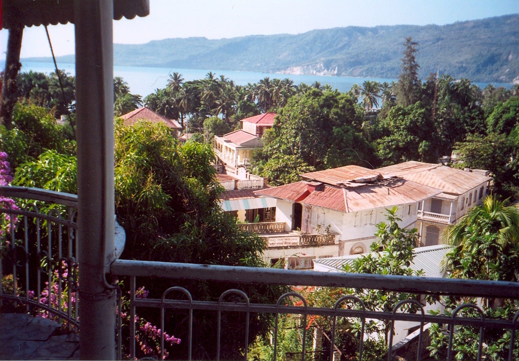 A hillside town of faded colourful buildings sloping down to a bay
