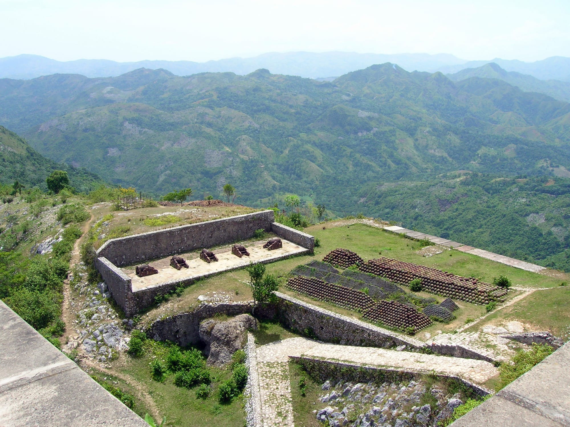 Rows of iron cannon lined up on a stone terrace inside a fortress