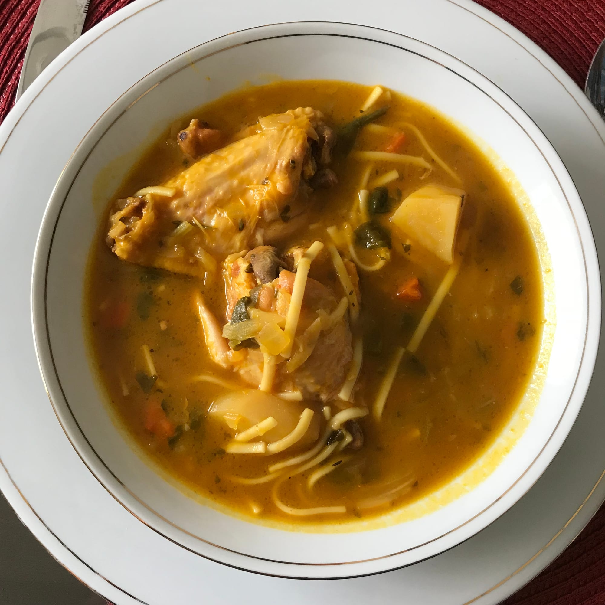 A bowl of orange squash soup with vegetables and meat