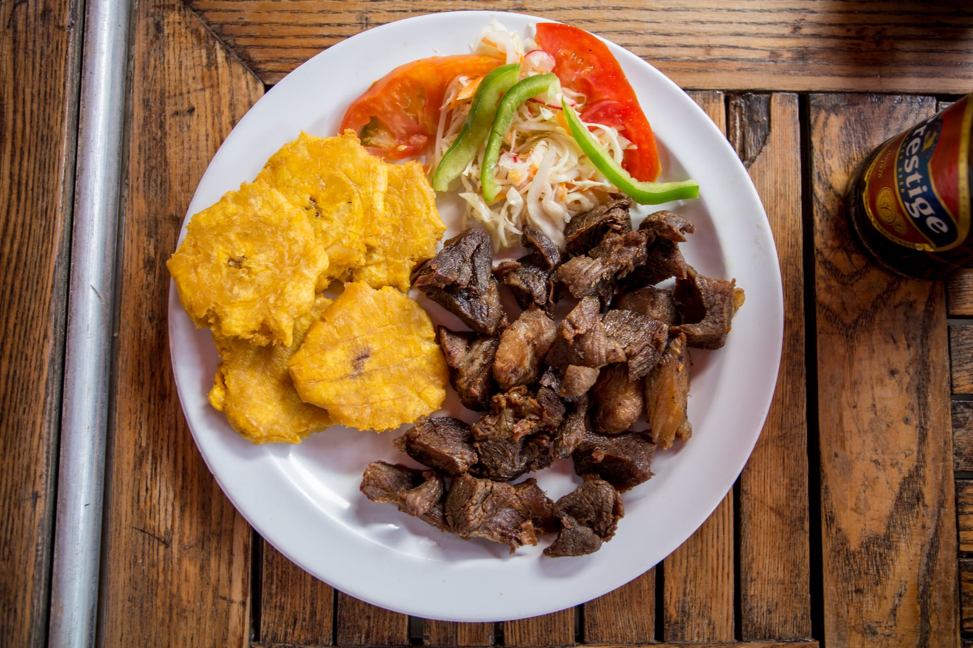 Pieces of fried pork served with rice, beans and fried plantain