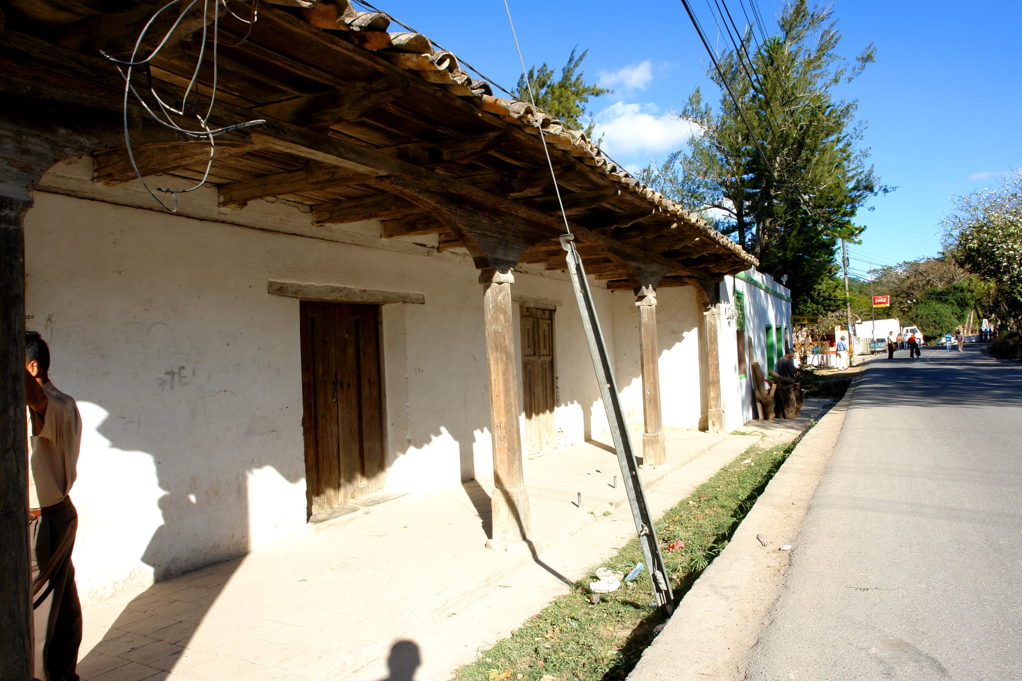 A whitewashed adobe house with a wooden tiled roof along a quiet street in the Honduran town of Ojojona