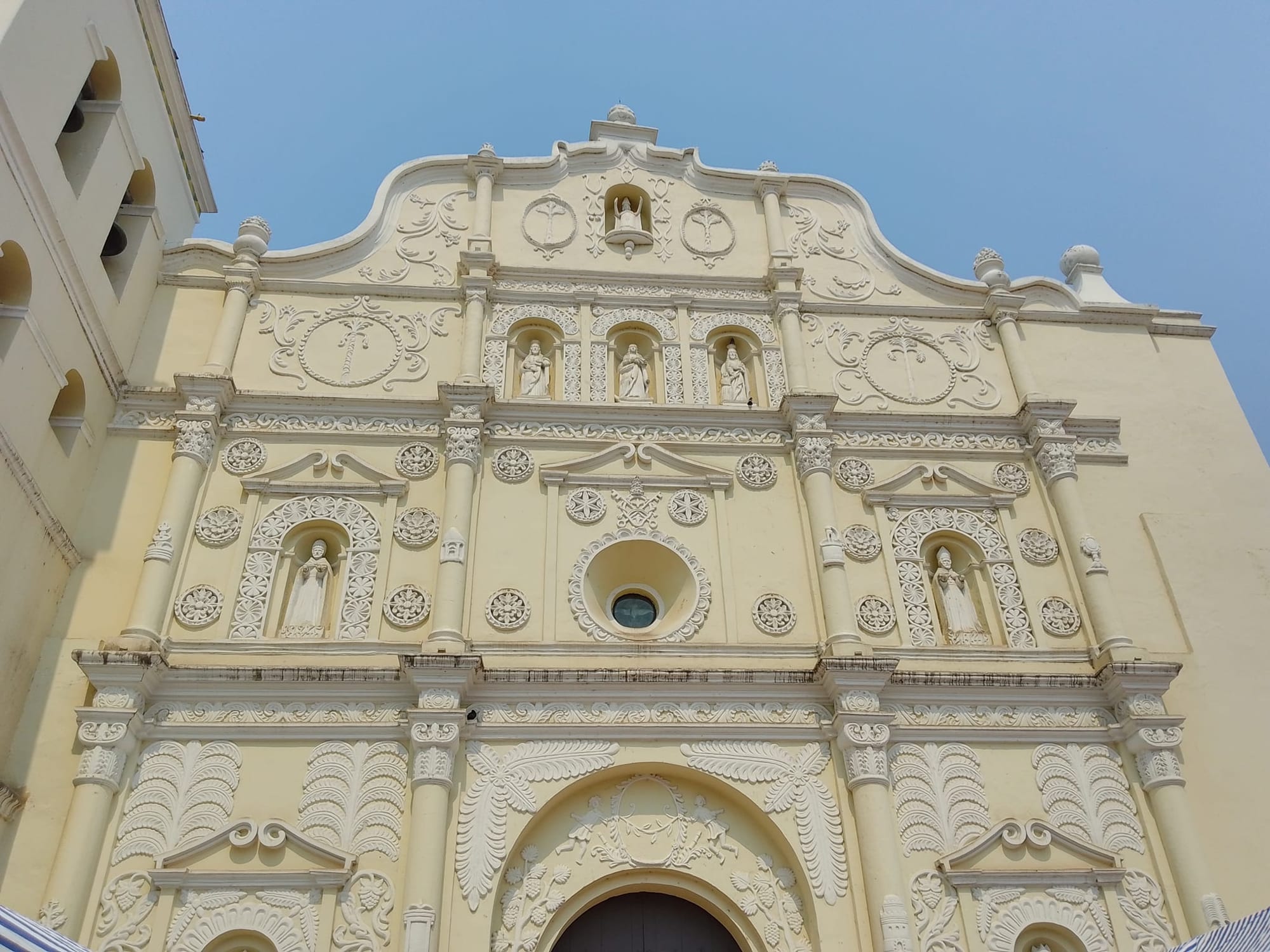 An ornately carved cream-coloured baroque cathedral facade with statues in niches