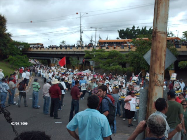 A street crowd of protesters with banners supporting Zelaya in 2009