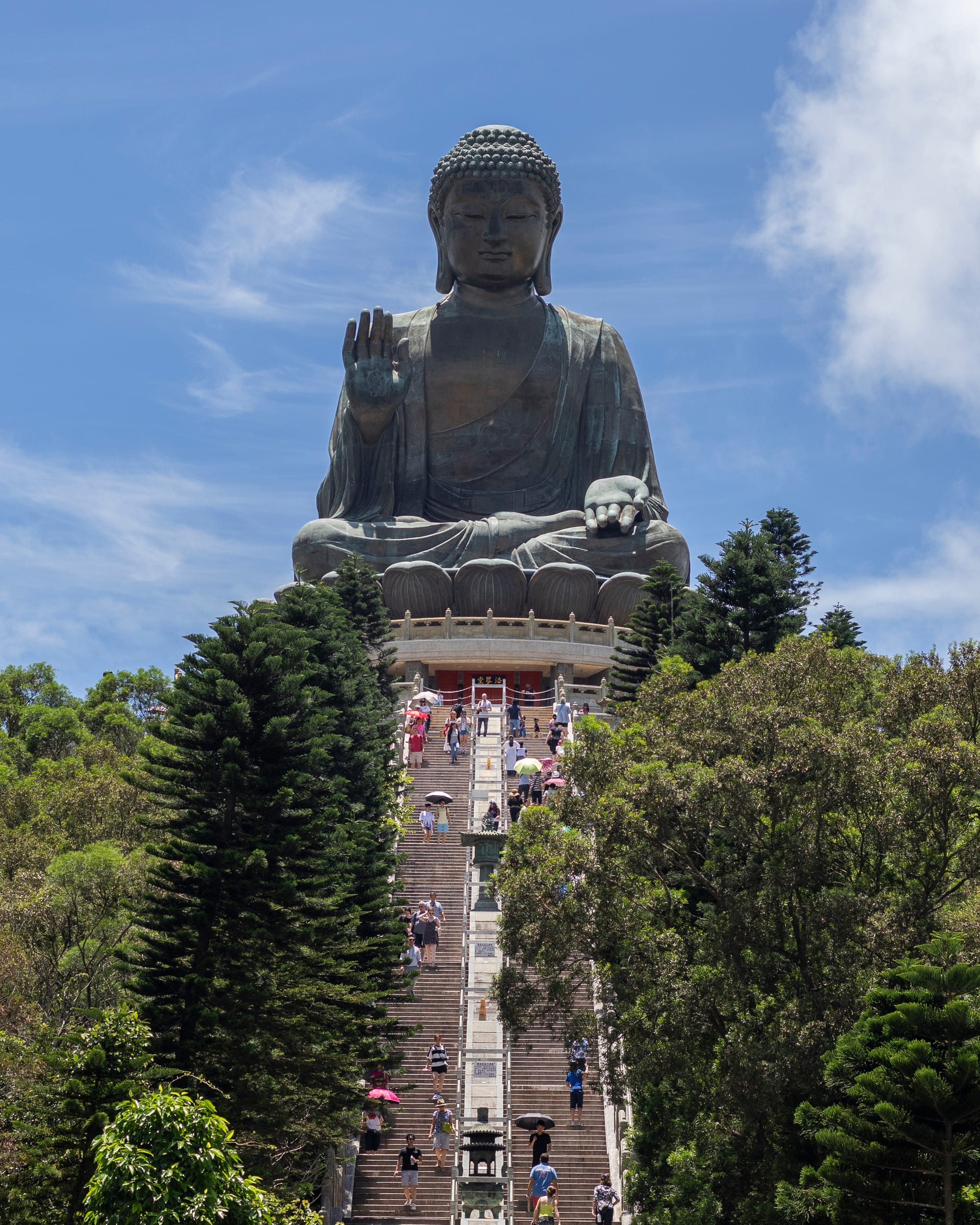 A very large seated bronze Buddha on a lotus throne atop a wide flight of steps