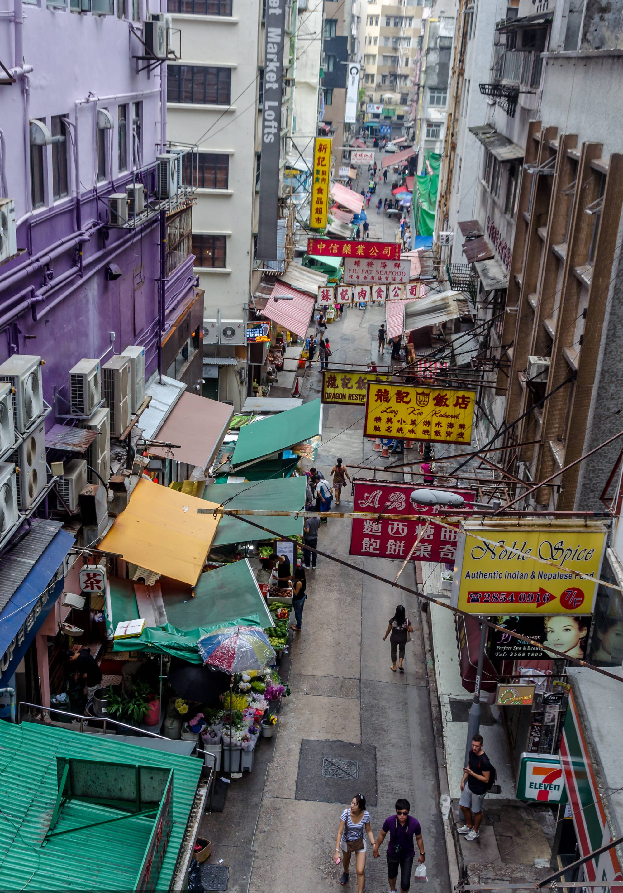 A steep, narrow street of shops and signs climbing between tall buildings