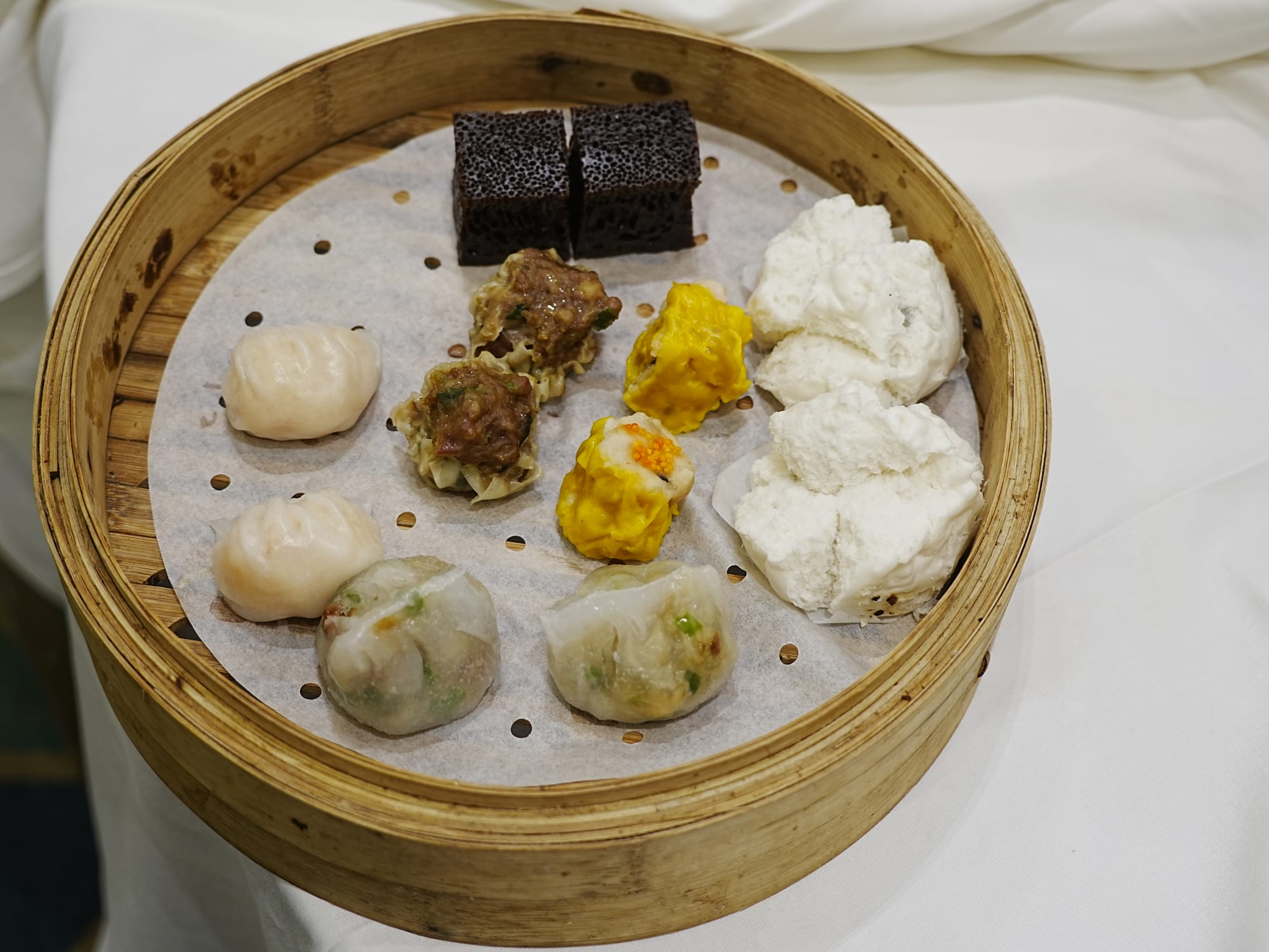 Bamboo steamer baskets filled with various dumplings and small plates
