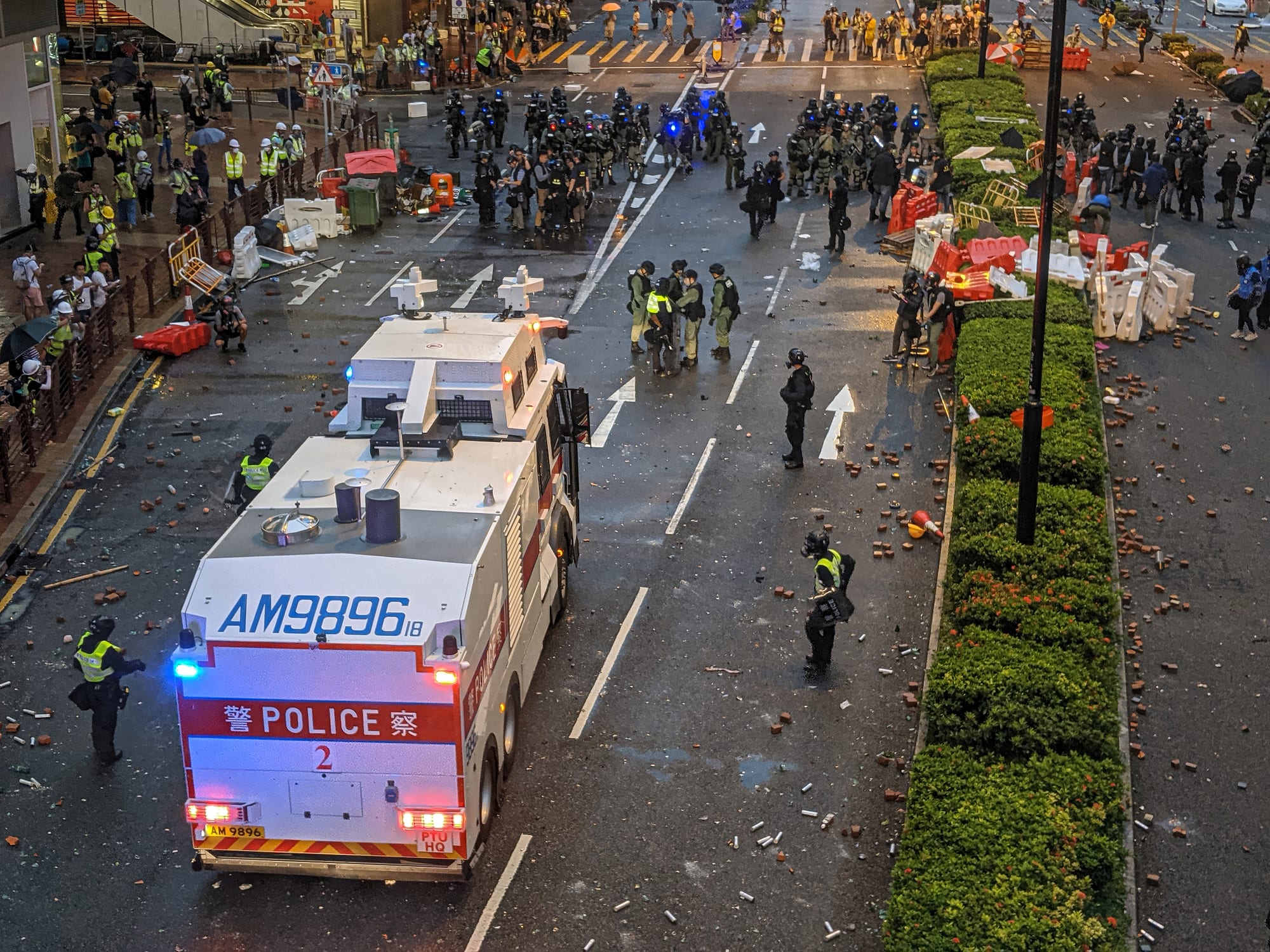 Riot police with a water cannon vehicle facing protesters on a Hong Kong street in 2019