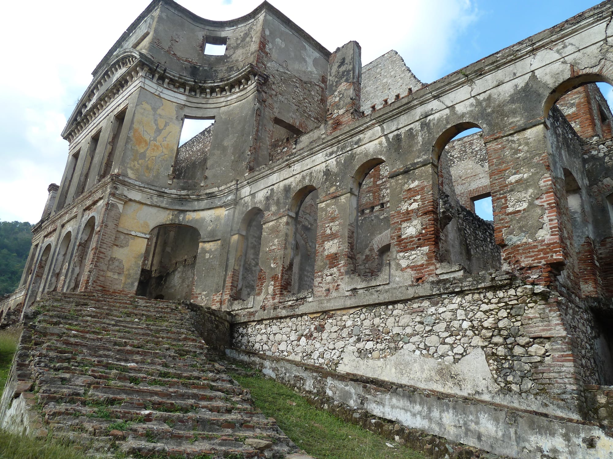The roofless ruins of a large palace with arched windows, crumbling plaster and a broad stone staircase