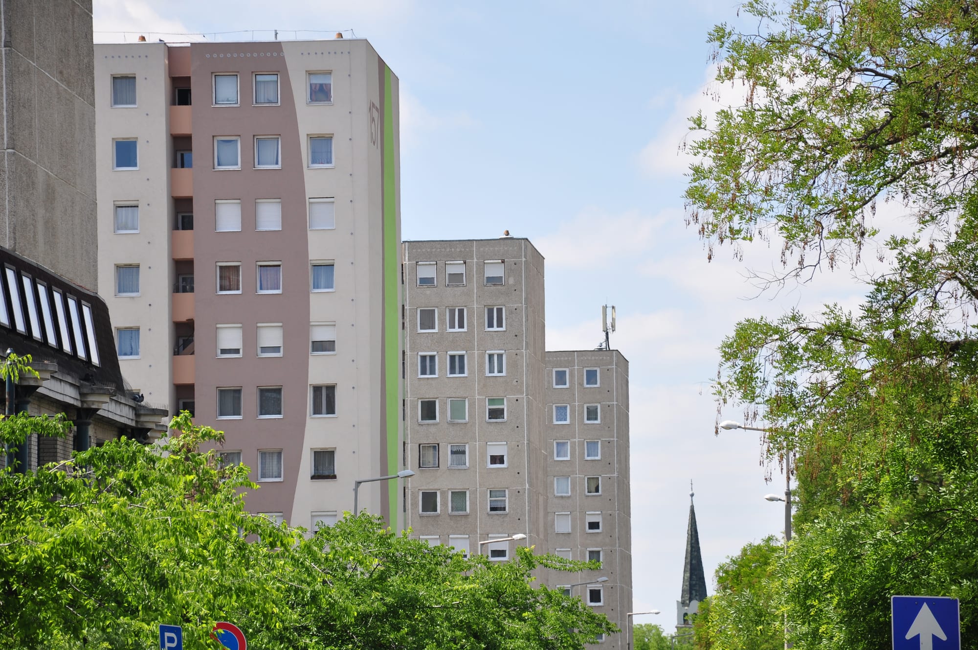 Renovated concrete panel apartment blocks in a residential street in Budapest, painted in cream and green with trees in front