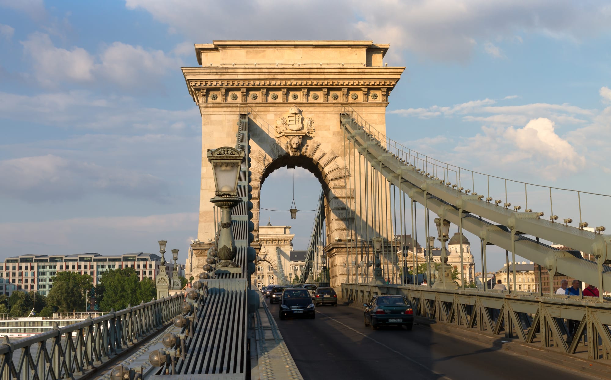 A 19th-century suspension bridge with stone lions and towers spanning a wide river