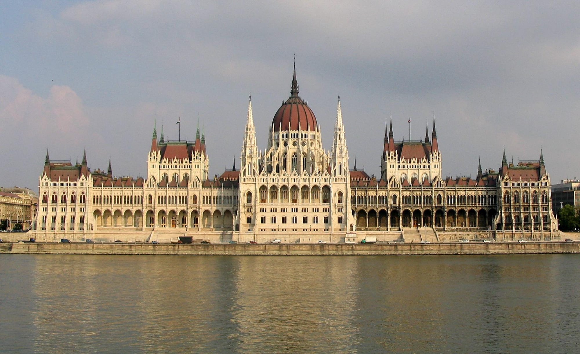 A vast neo-Gothic parliament building with a central dome and spires along the Danube riverbank