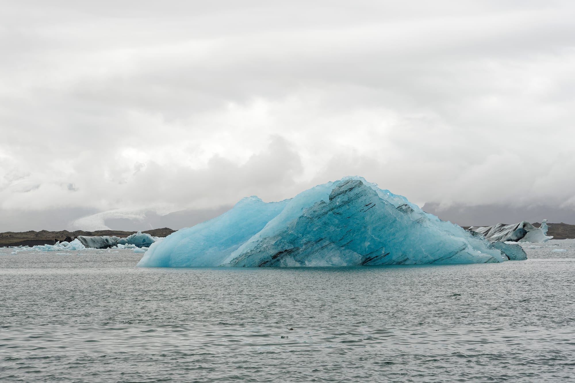 A lagoon full of blue and white icebergs with a glacier tongue behind