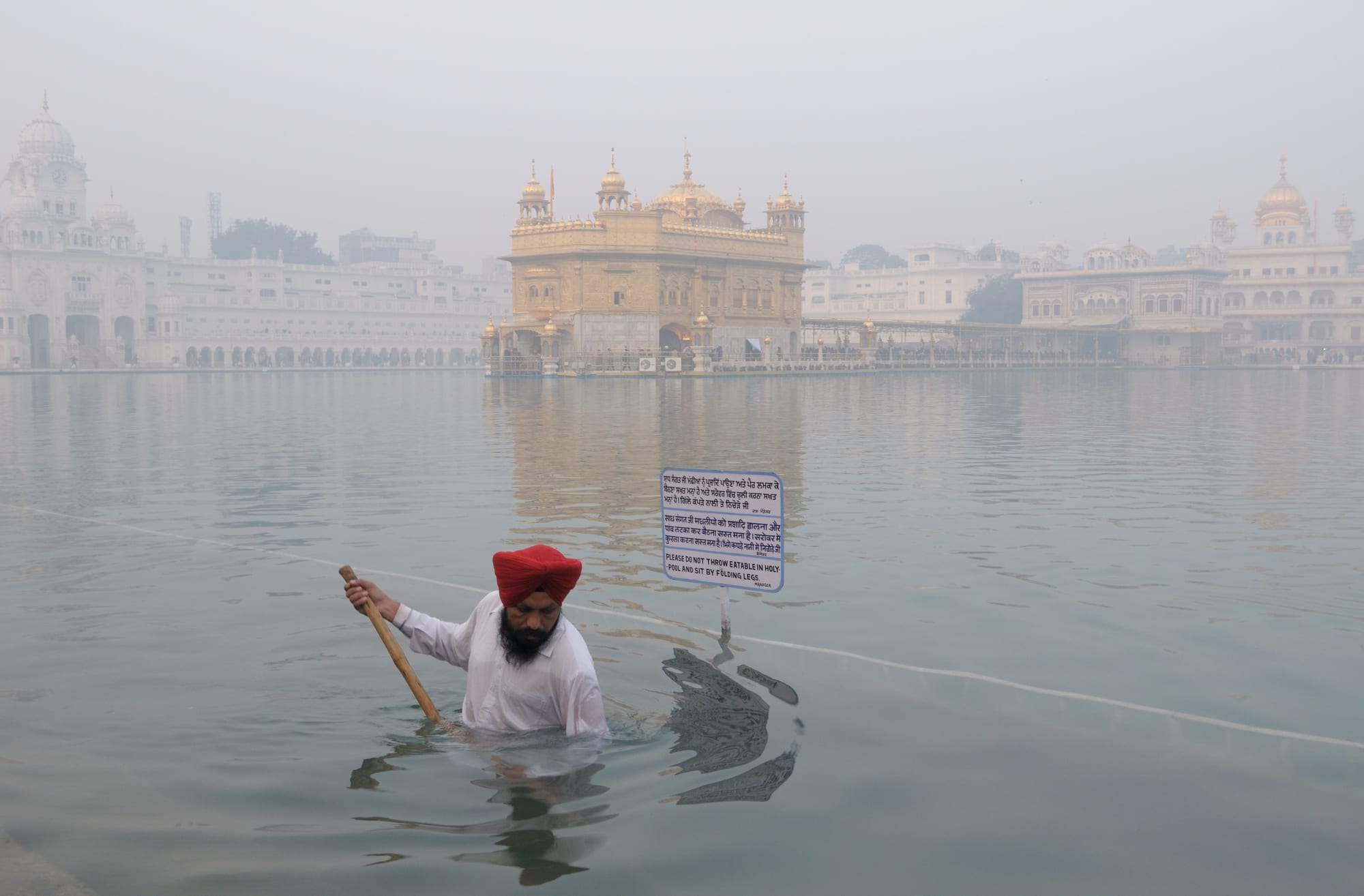 A golden domed temple on an island in a large square pool, linked by a causeway