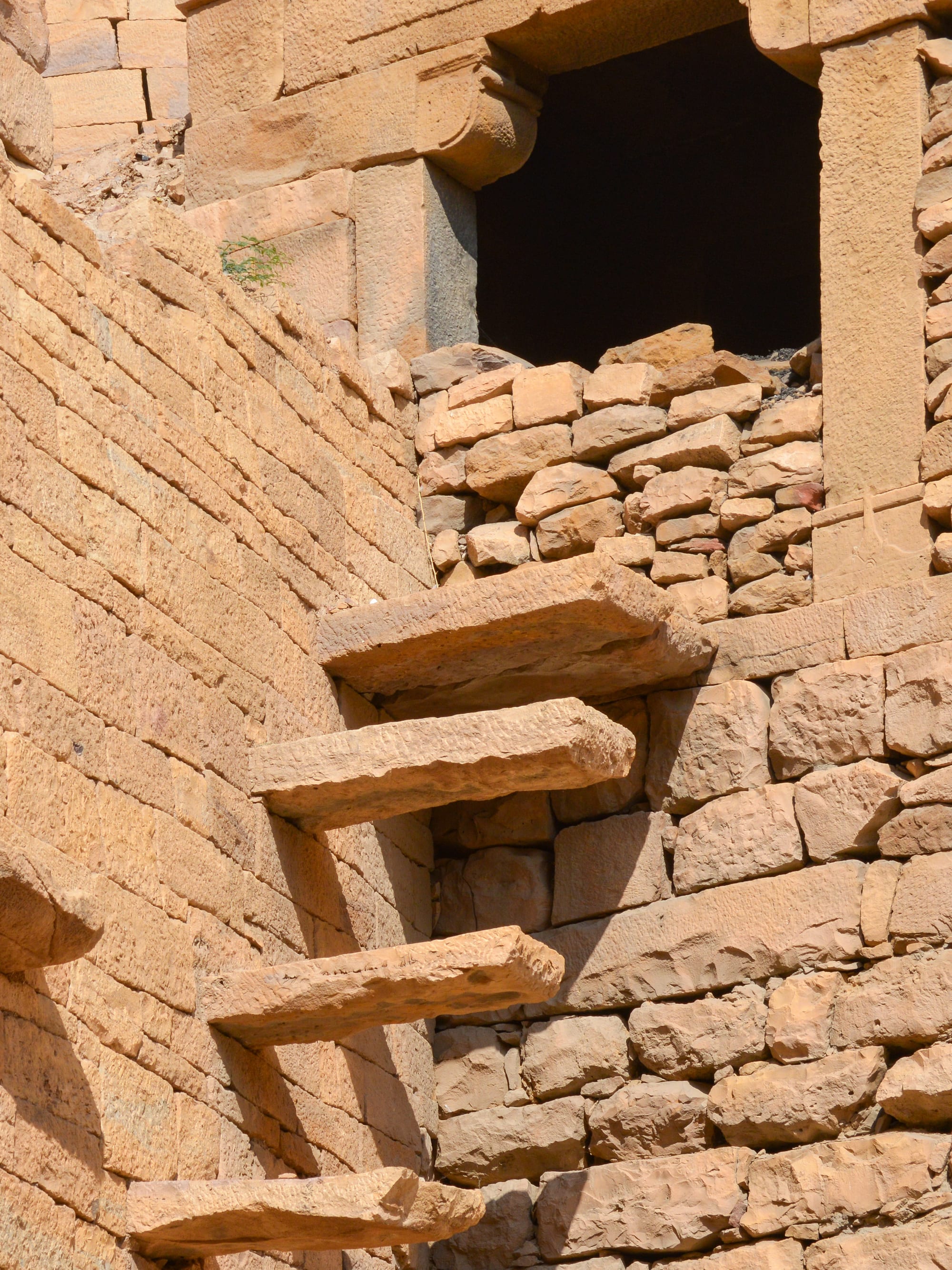 Worn golden sandstone steps and carved buildings inside a desert fort