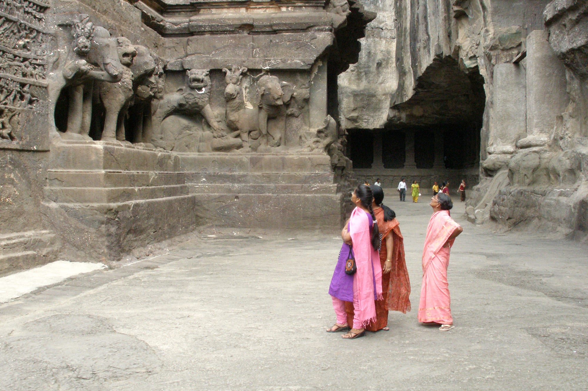 An enormous temple carved entirely downward out of a rock cliff, with courtyards and towers