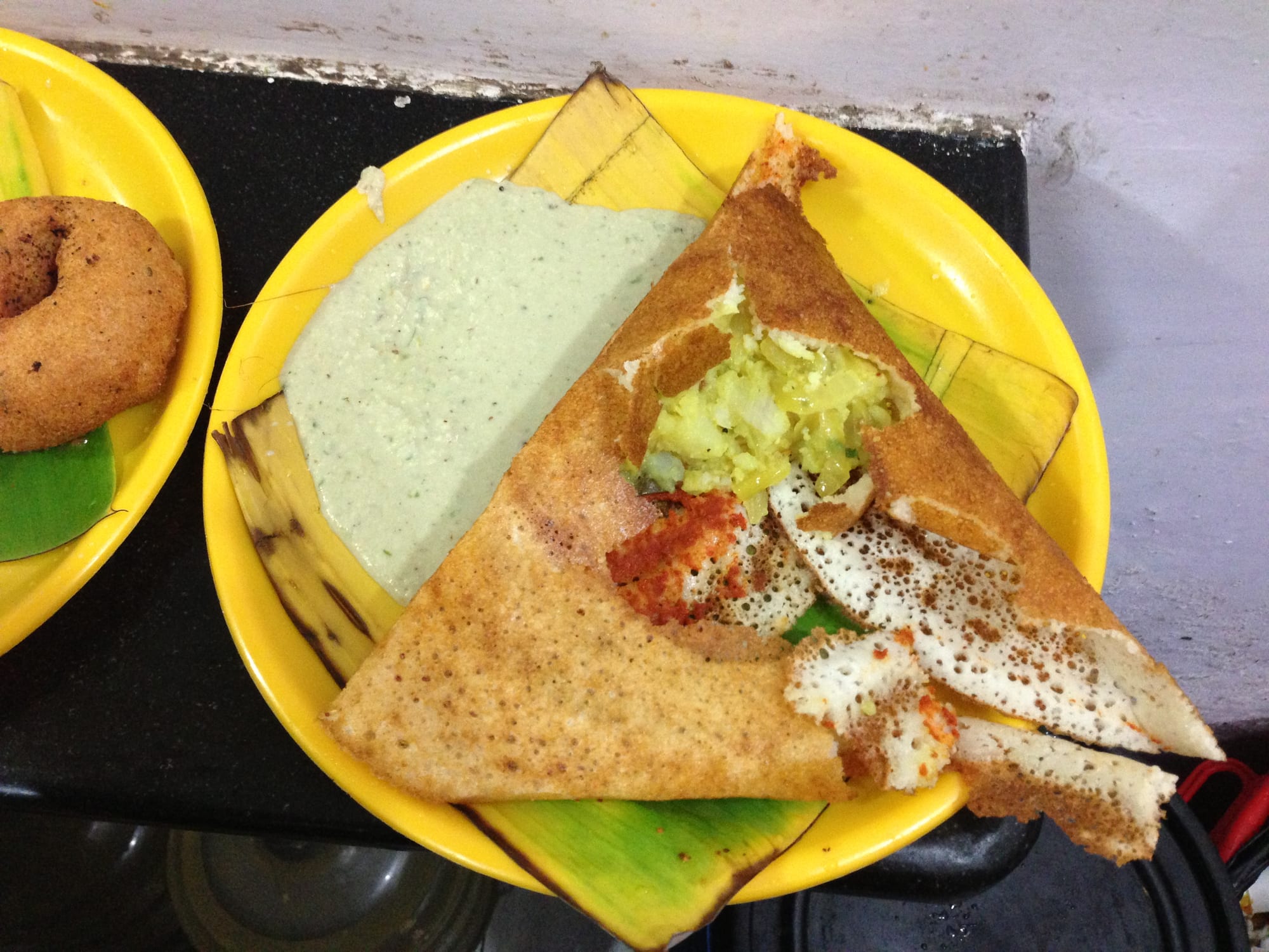 A large crisp folded crepe served with small bowls of chutney