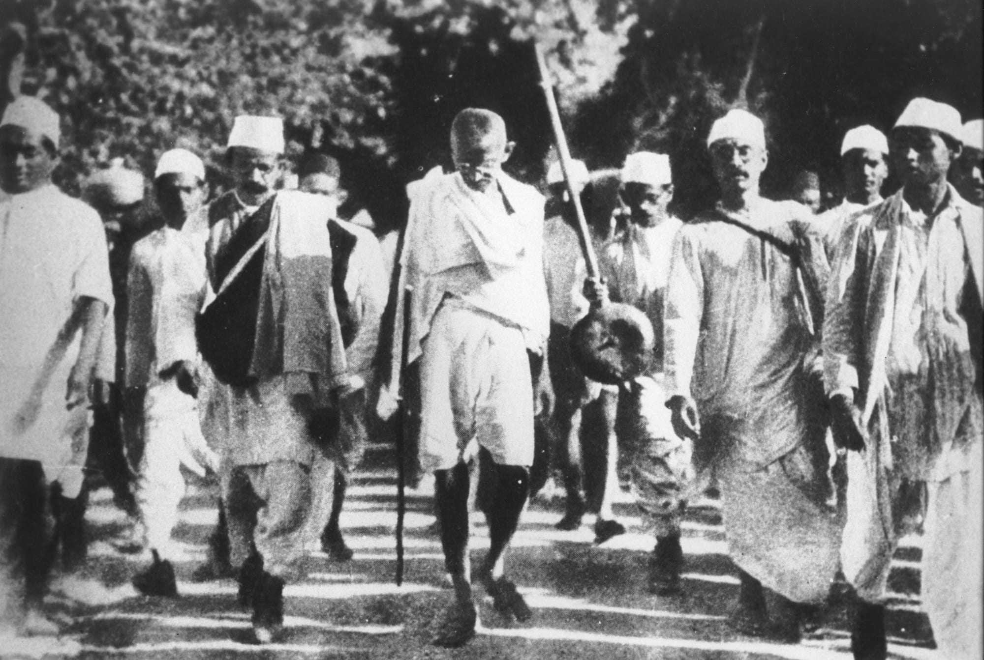 Gandhi walking with a staff at the head of a line of followers during the 1930 Salt March
