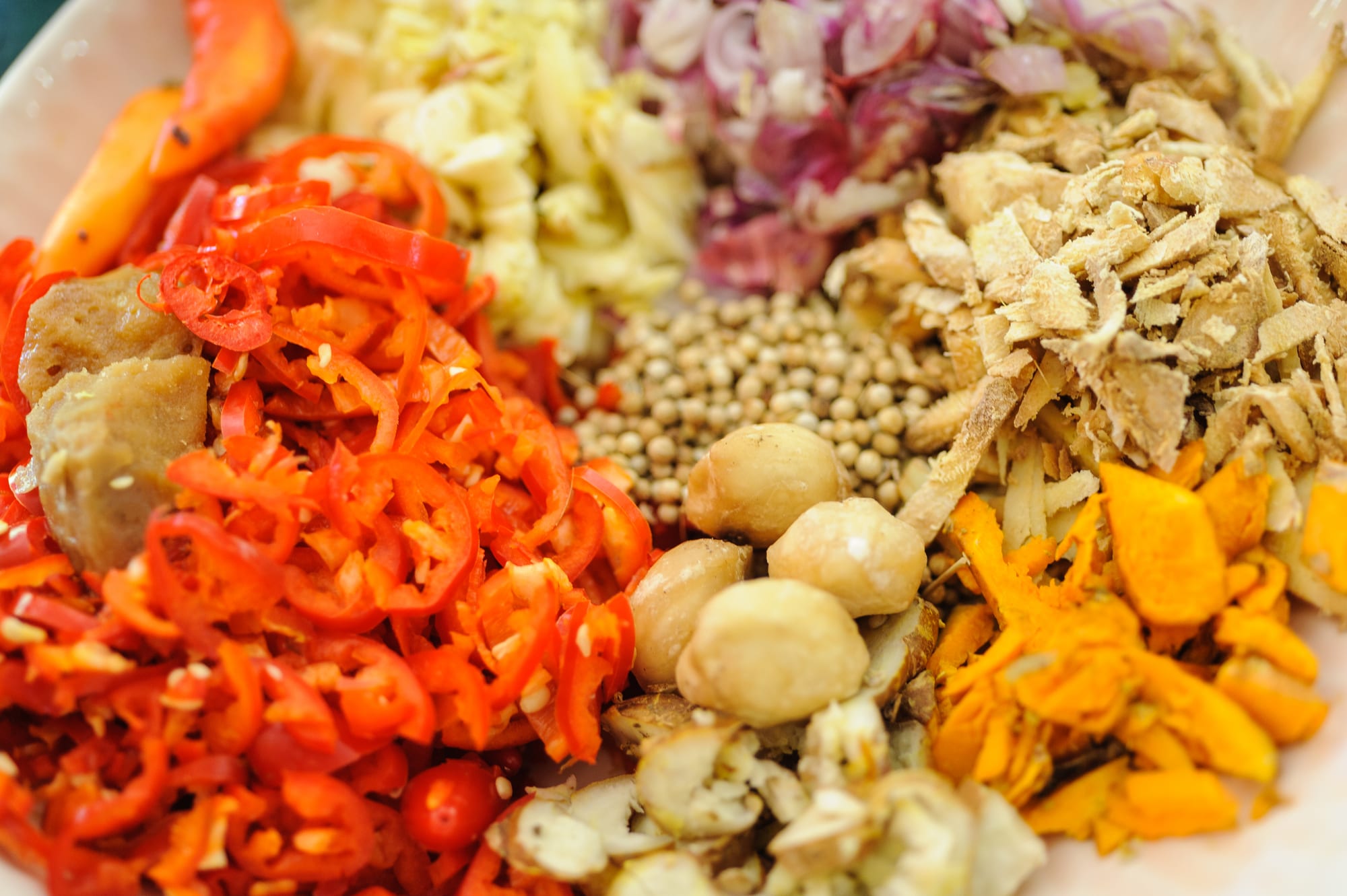 A market table covered in bowls of chillies, spices and roots