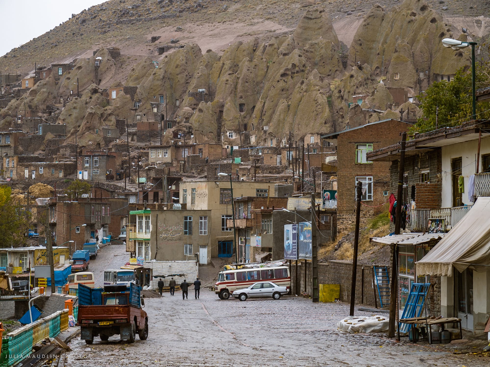 Homes carved into tall cone-shaped rock formations on a village hillside