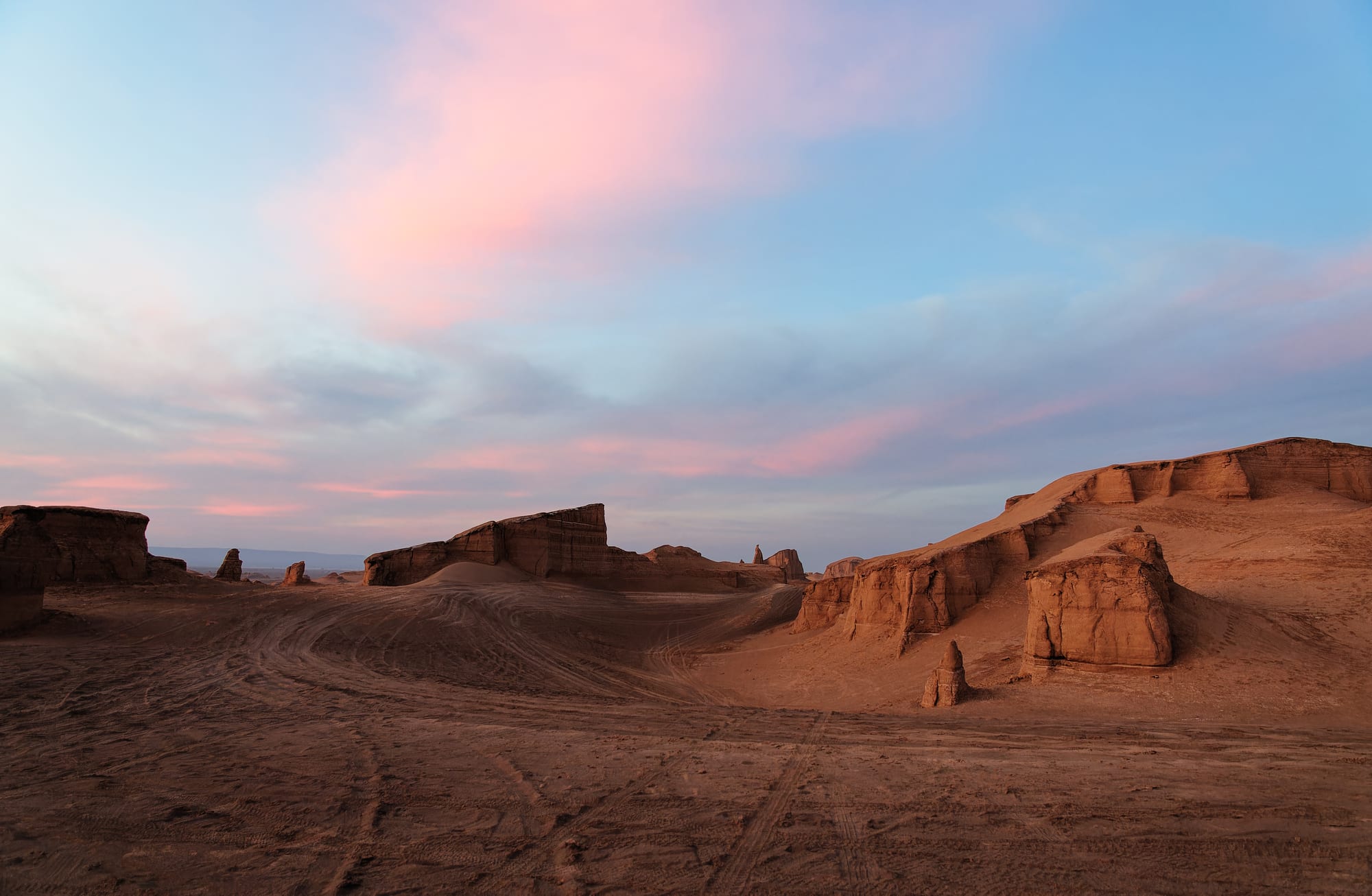 Rows of tall, wind-eroded sand-and-clay ridges stretching across a desert under a clear sky