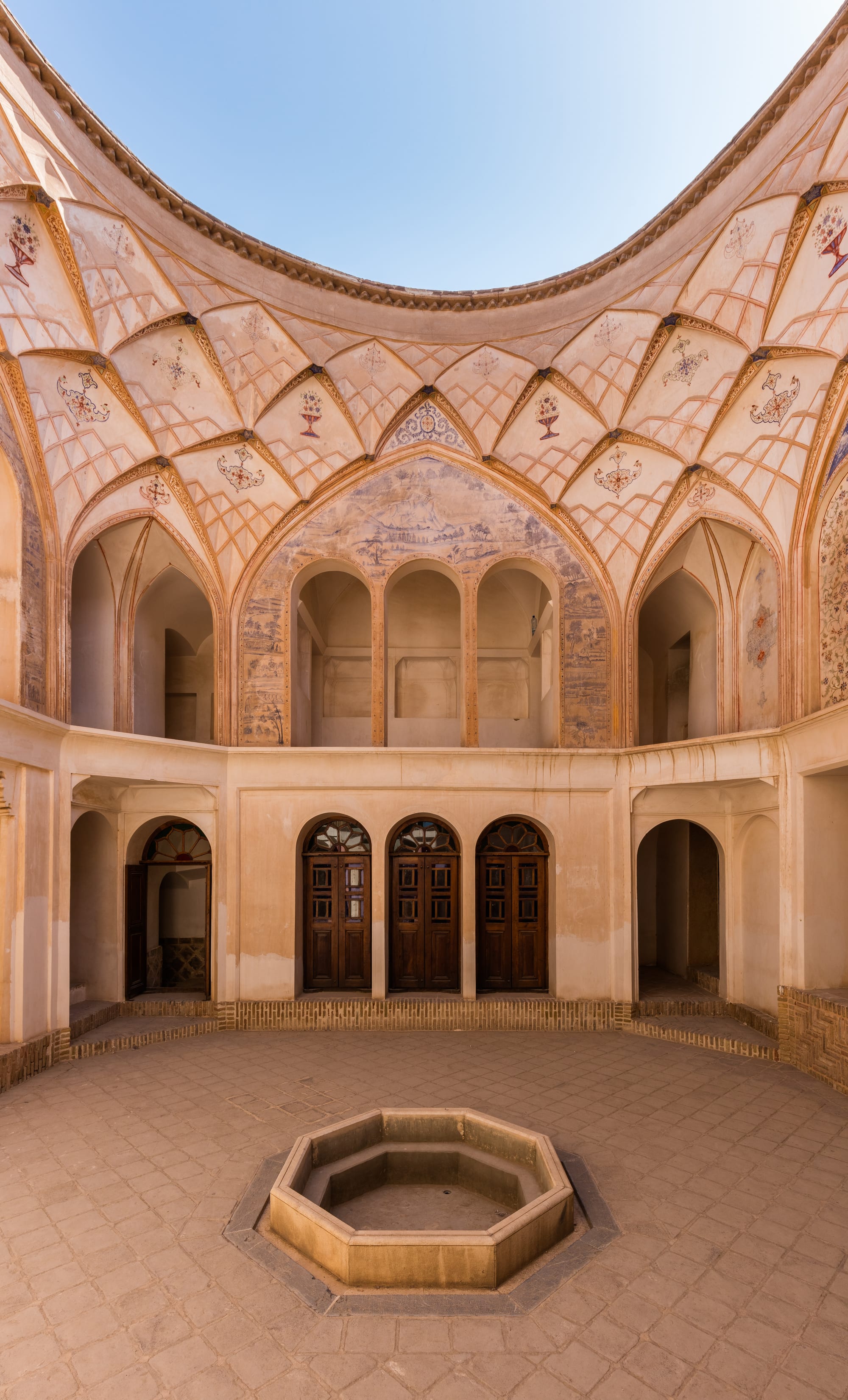 An ornate courtyard house with carved stucco, coloured glass, and a central pool