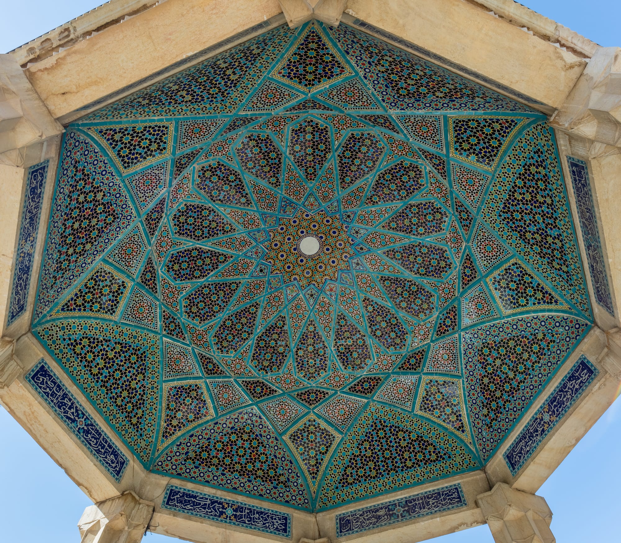 An open domed pavilion over a marble tomb in a garden of cypresses and pools